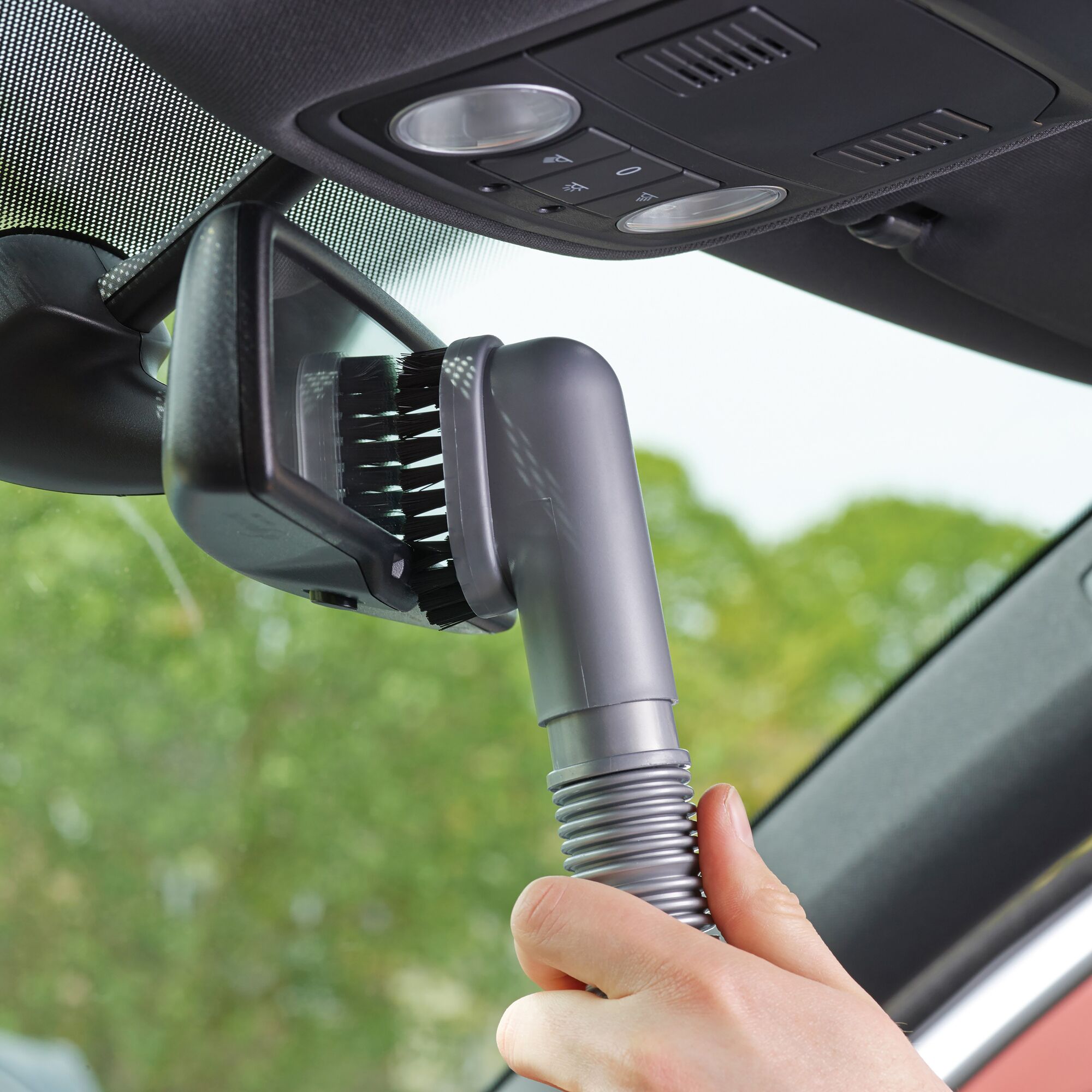 BLACKDECKER ADV1200 handheld vacuum brush cleaning a car rearview mirror, close-up angle.
