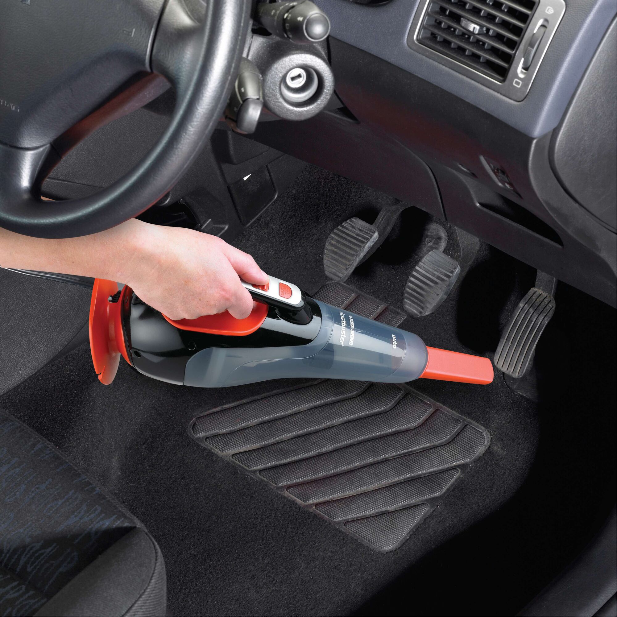 BLACKDECKER ADV1210 handheld vacuum cleaner used on car floor mat, close-up angle.