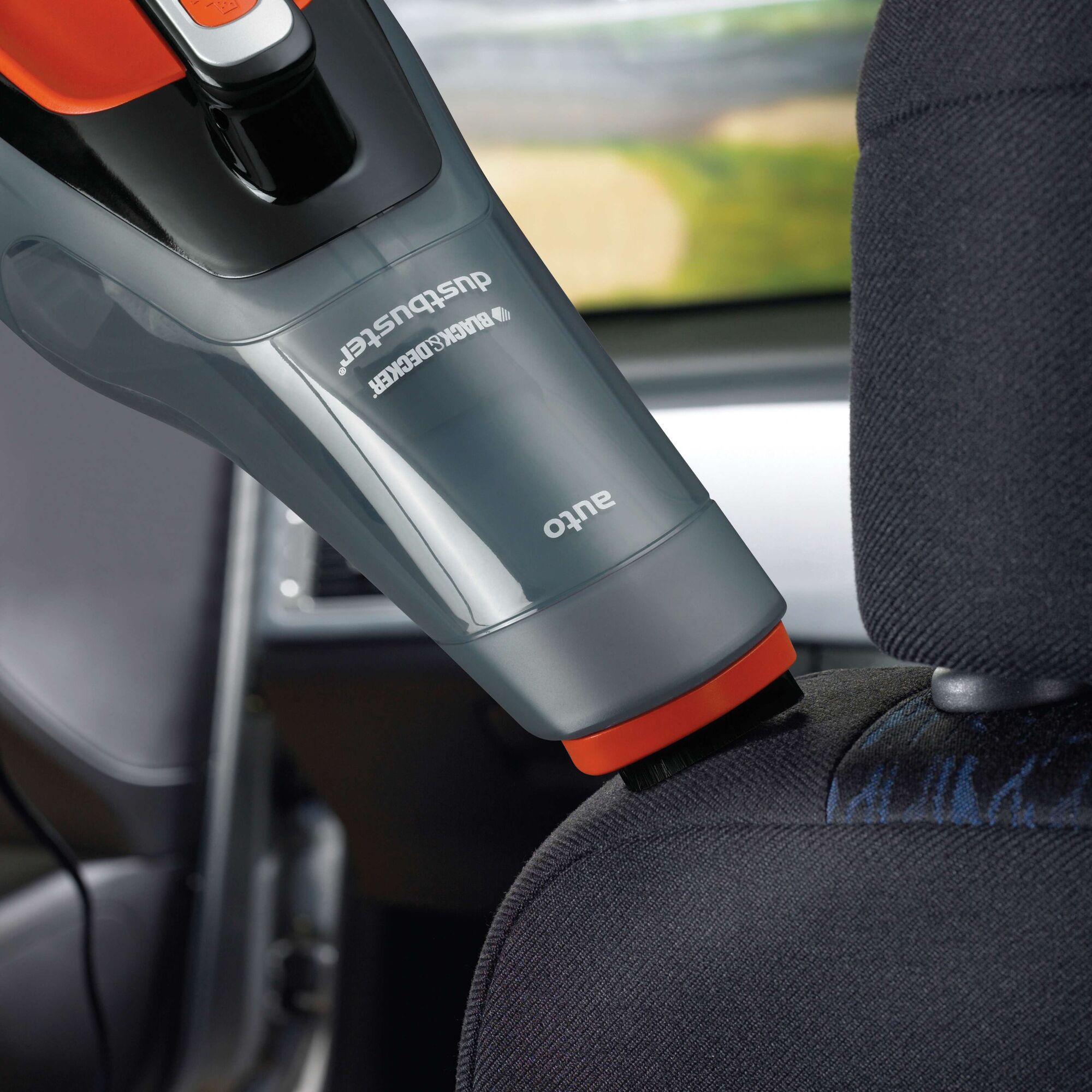 A BLACK+DECKER handheld car vacuum cleaner, model ADV1210, being used to clean the upholstery of a car seat.