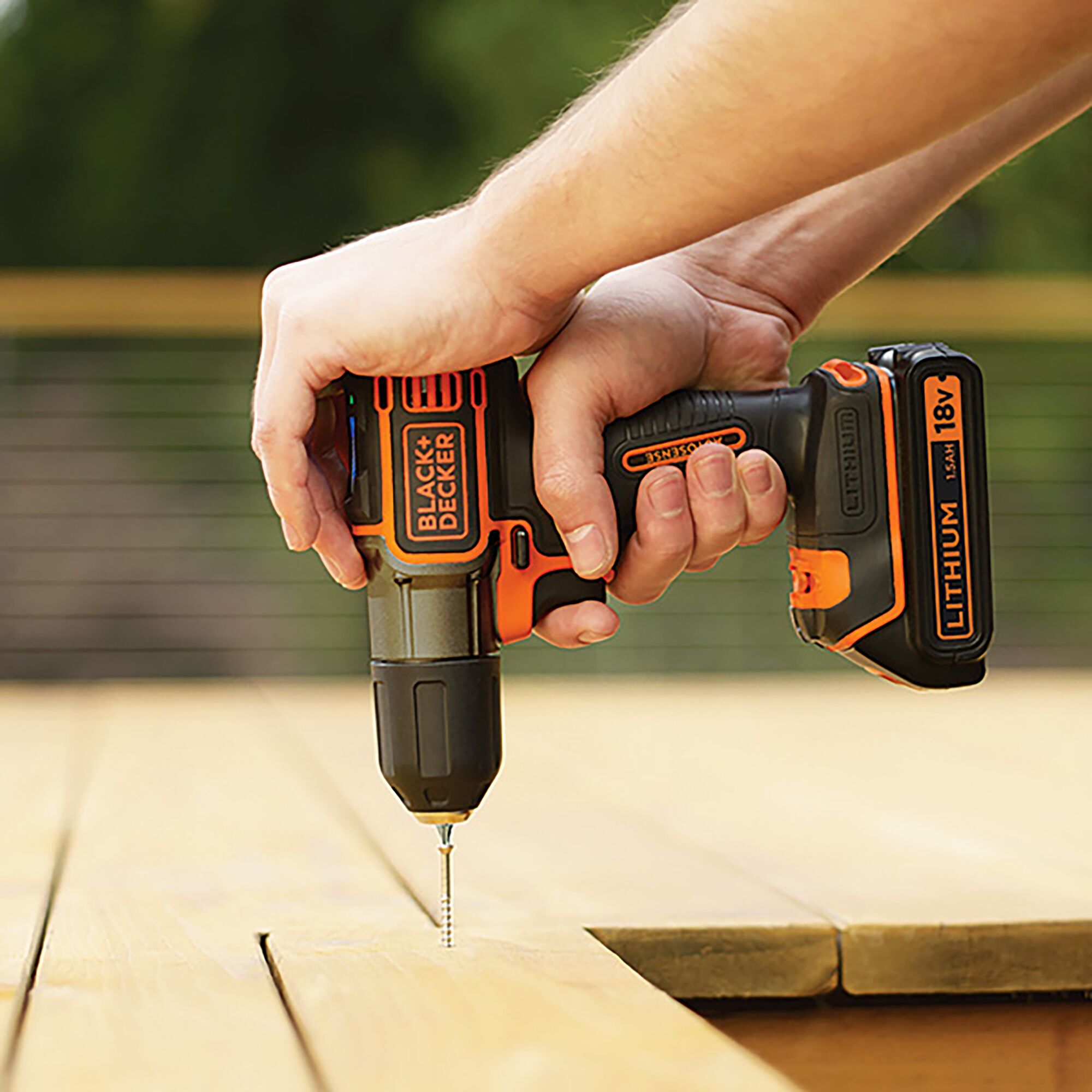 BLACKDECKER AUTO01 cordless drill, orange and black, in use on wood surface, outdoor angle.
