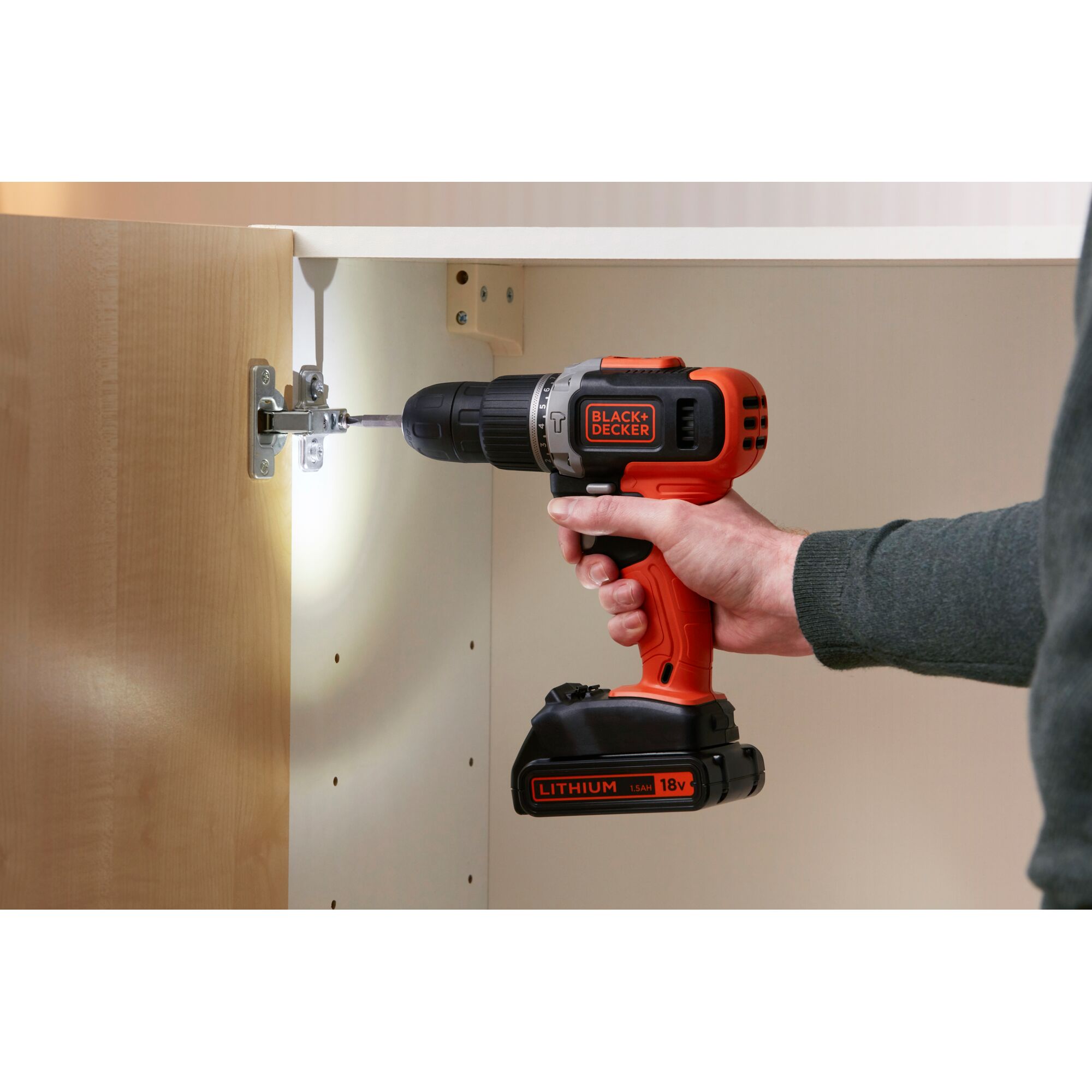 BLACK+DECKER BCD003C1 cordless drill used to install cabinet hinge, orange and black design, side angle.