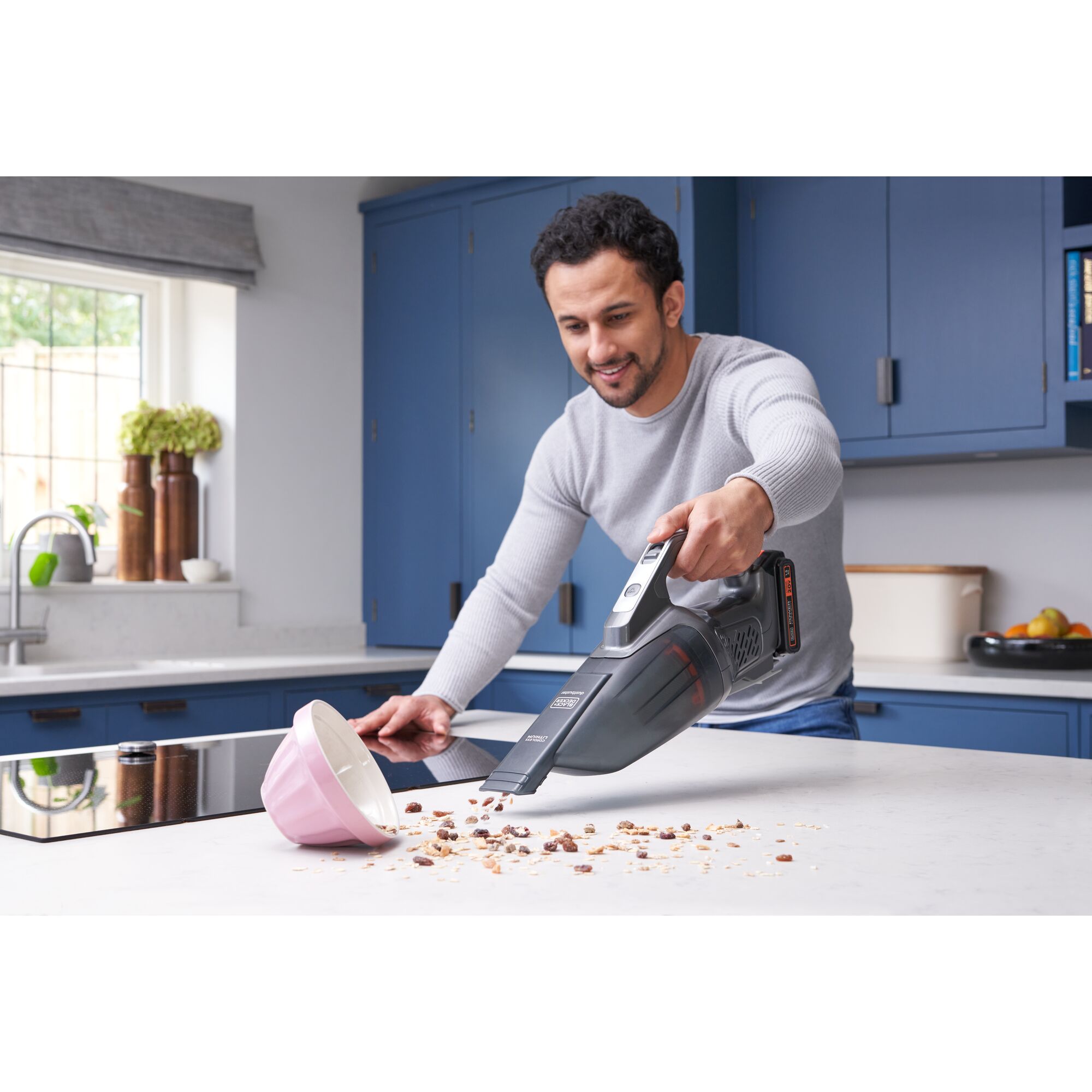 Person using BLACKDECKER BCHV001D1E handheld vacuum cleaner on kitchen counter with spilled cereal and a pink bowl.