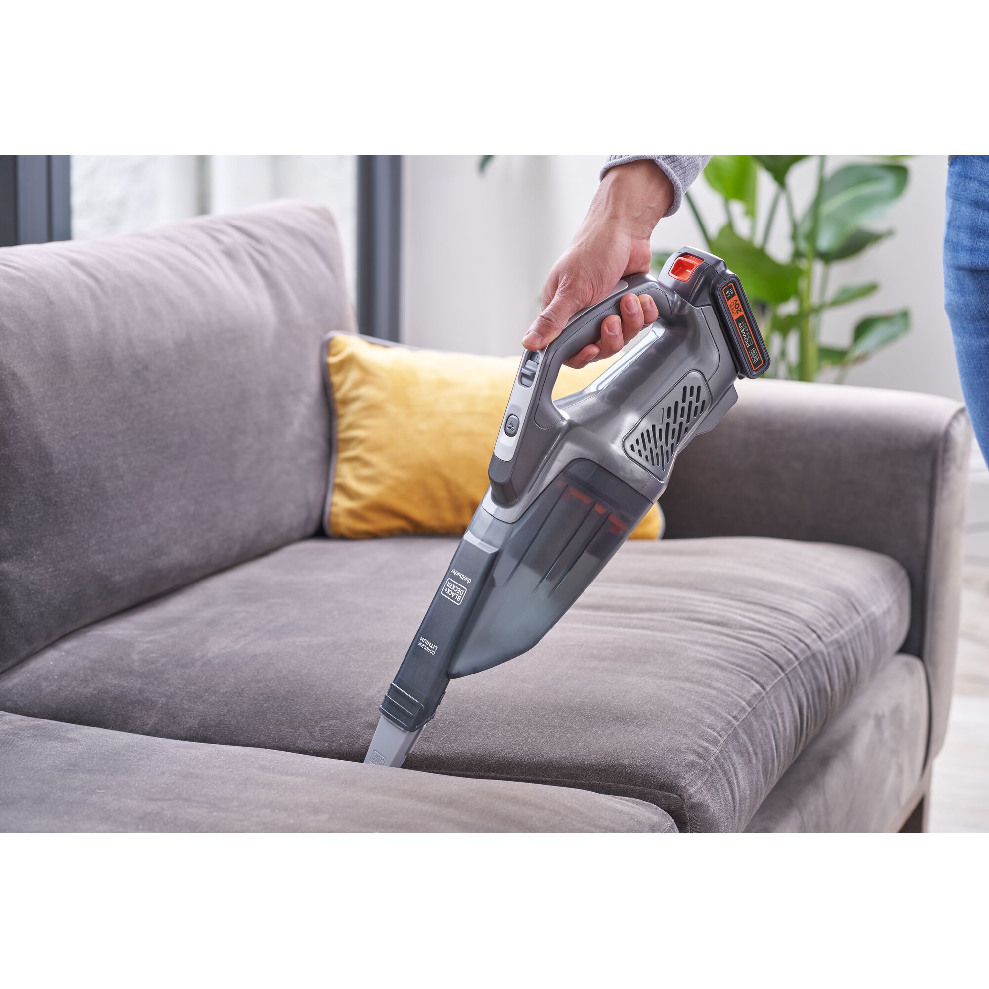 BLACKDECKER BCHV001D1E handheld vacuum cleaner used on a grey sofa indoors.