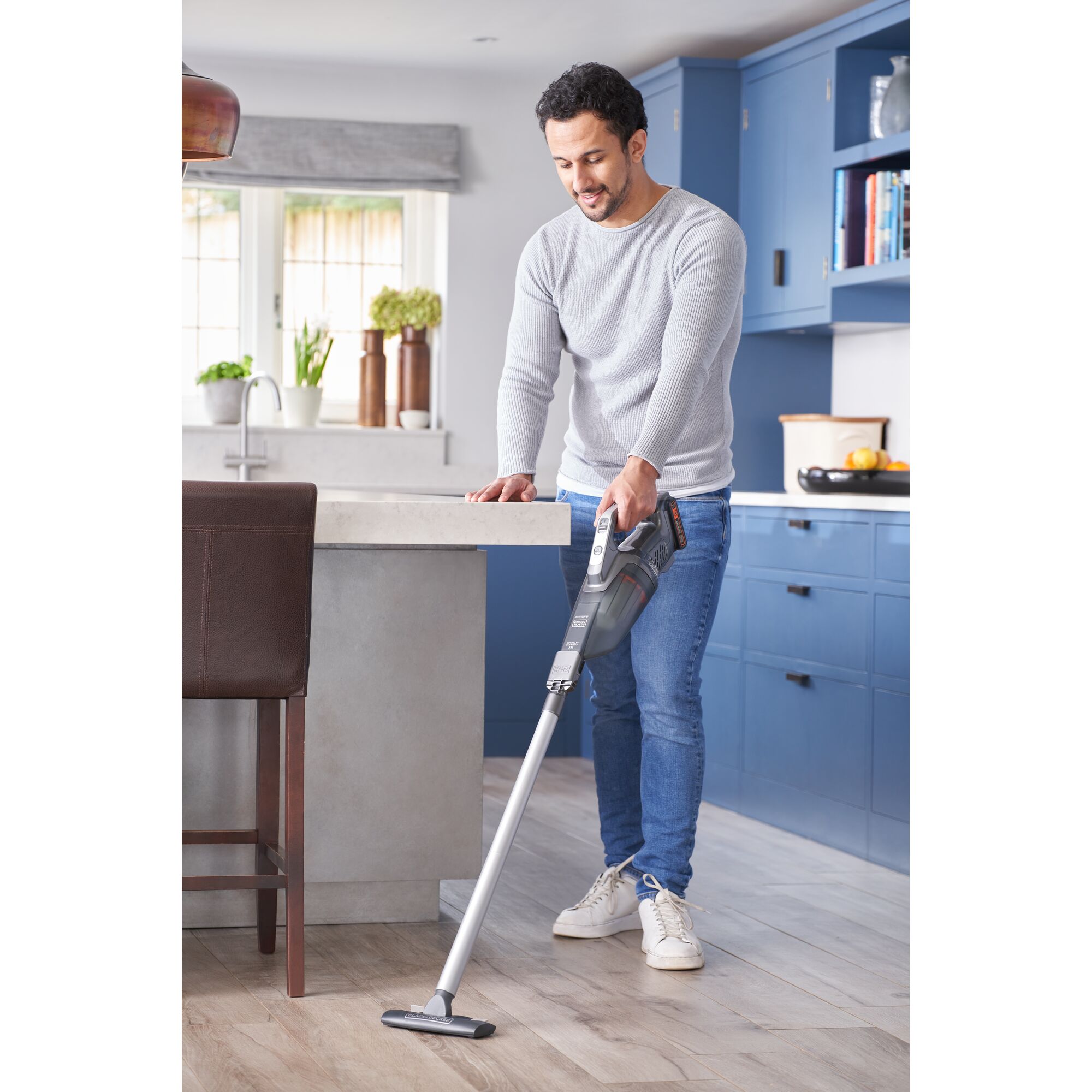 BLACKDECKER BCHV001D1E cordless stick vacuum used on kitchen floor in modern blue and white kitchen.