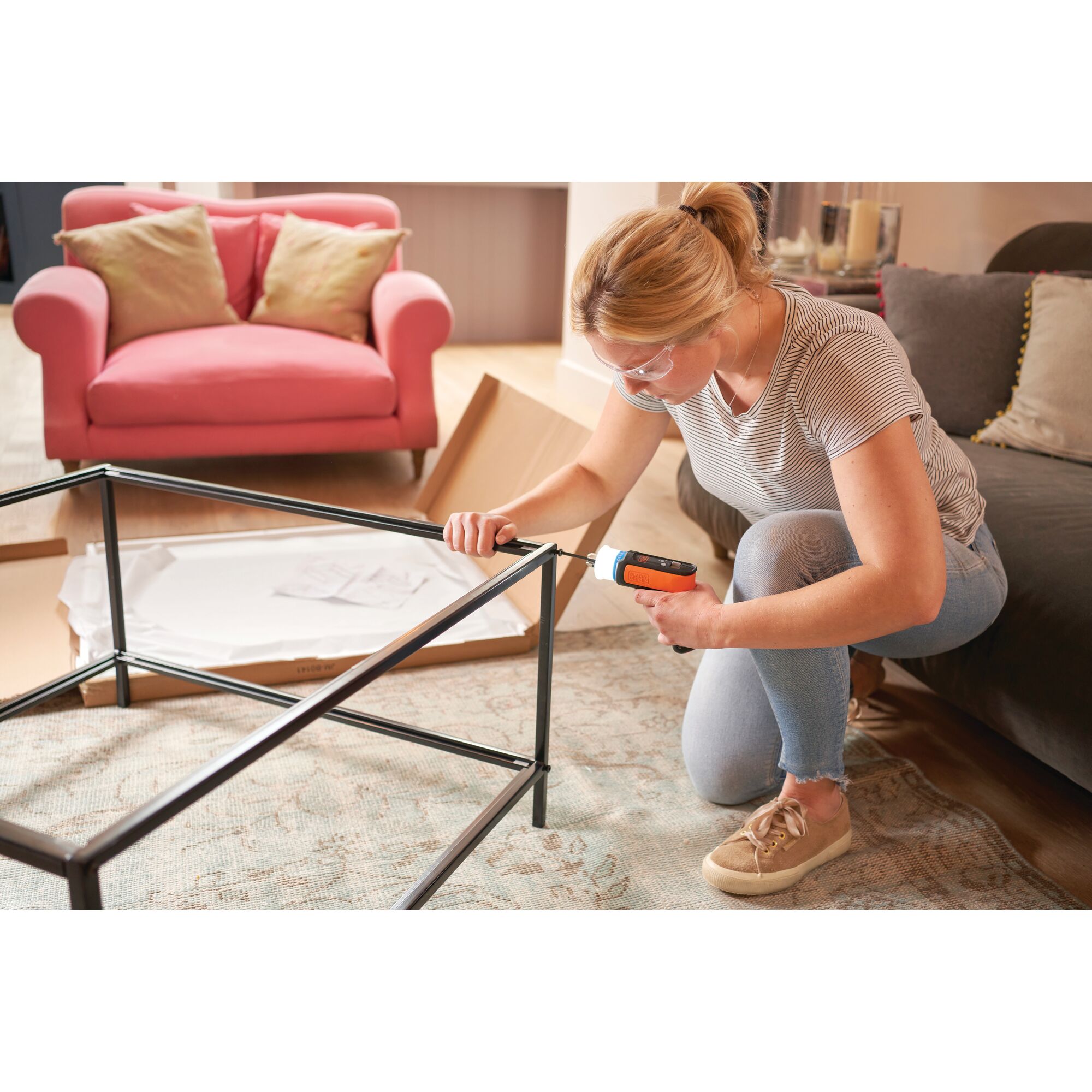 BLACKDECKER BCRTA601 cordless screwdriver used to assemble metal table frame in living room setting.