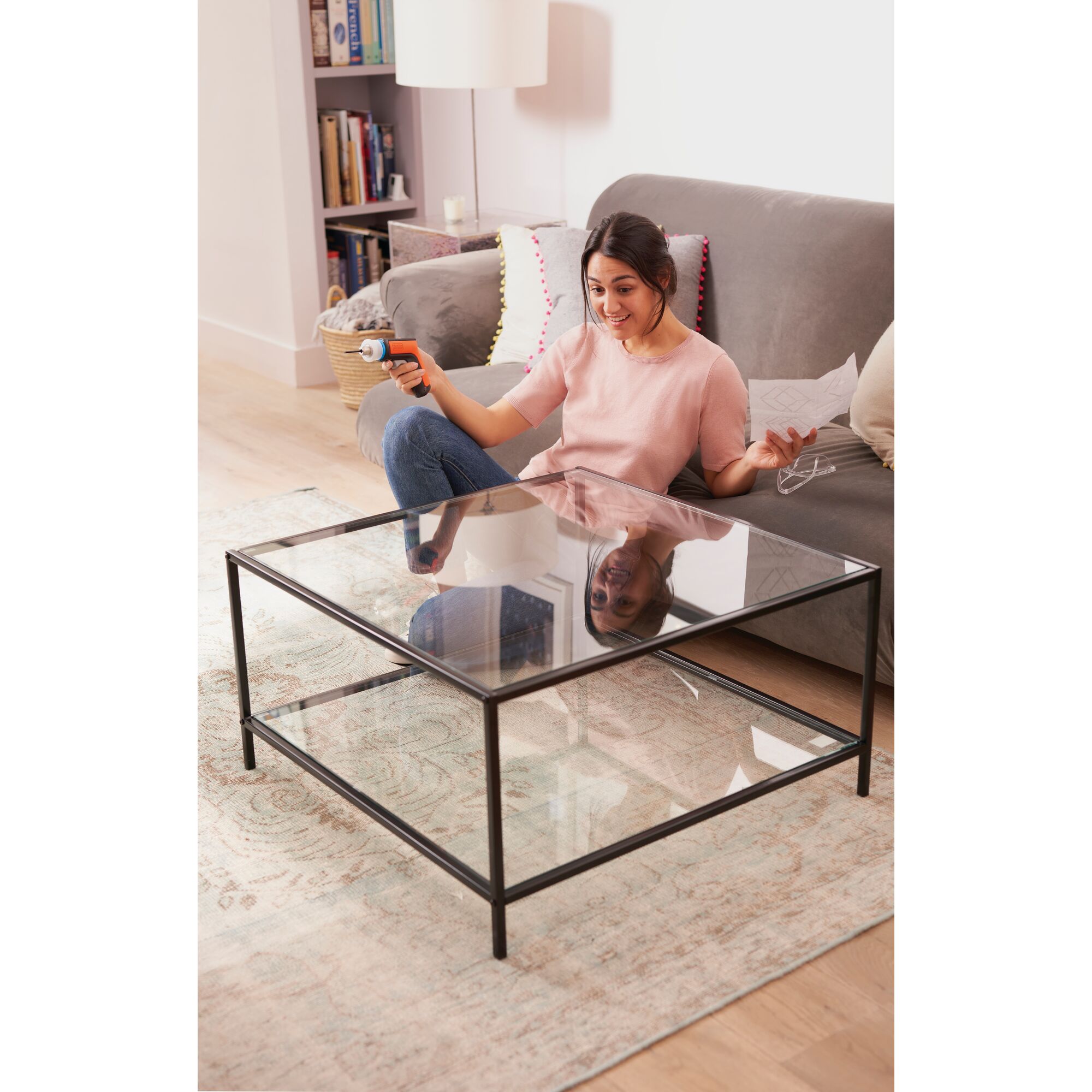BLACKDECKER BCRTA601 rotary tool in use assembling glass coffee table on living room rug.