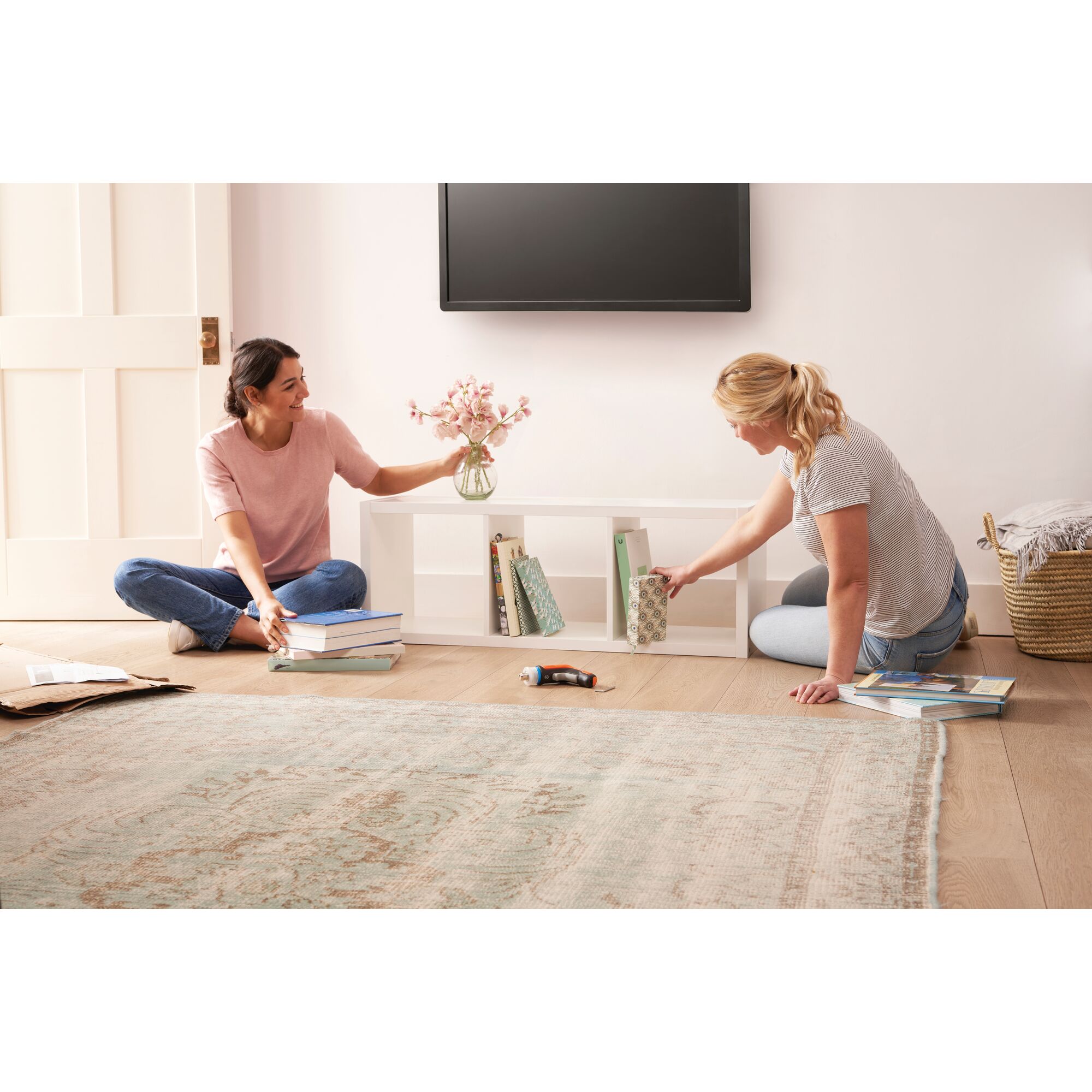 BLACKDECKER BCRTA601 cordless screwdriver on floor in living room with people organizing books and shelf.