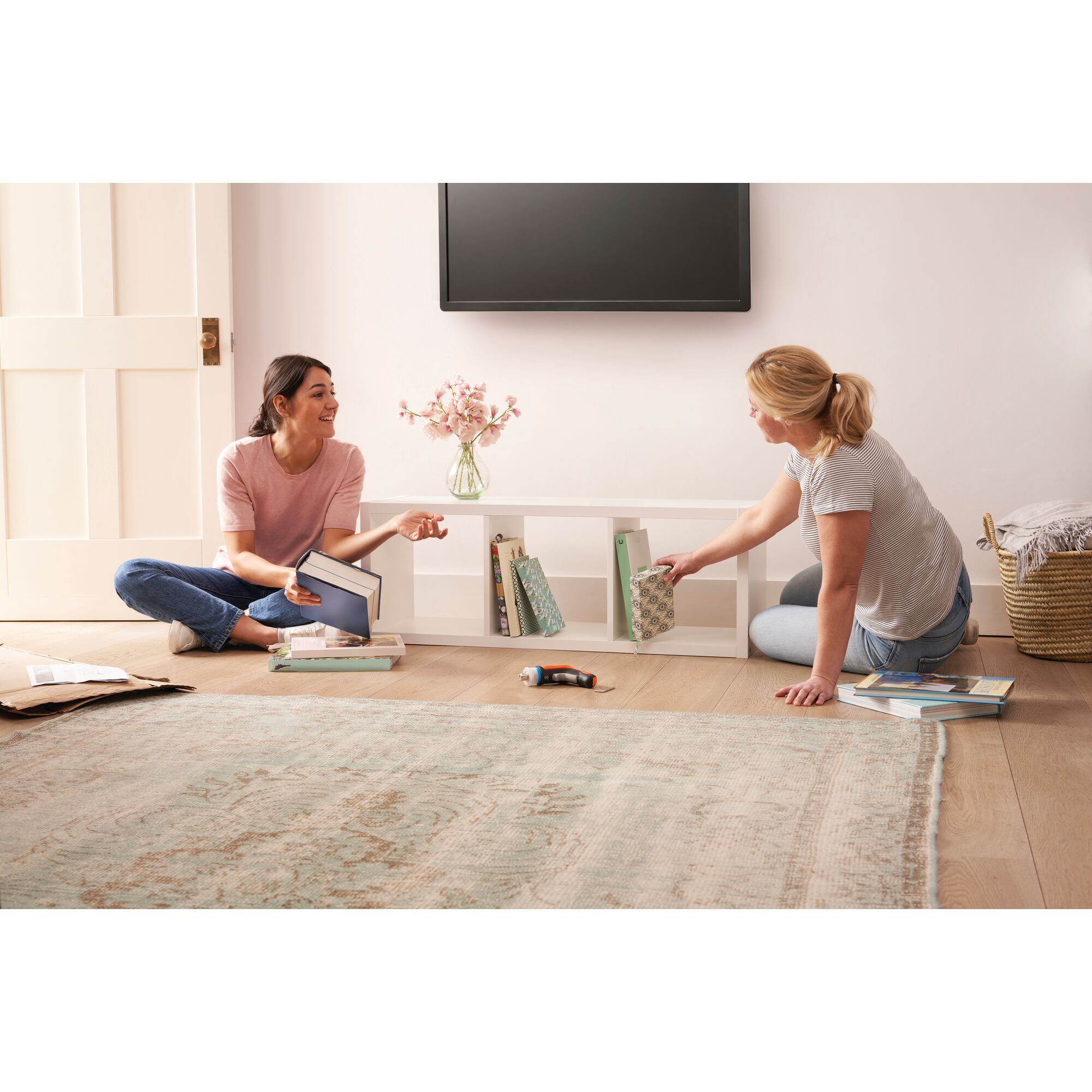 BLACKDECKER BCRTA601 cordless screwdriver on floor in living room with two people assembling white bookshelf.