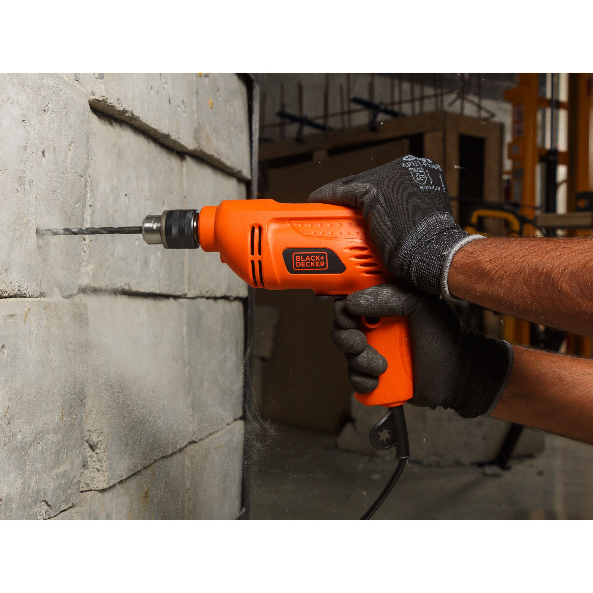 BLACKDECKER BD10RD orange corded drill being used on a concrete wall, close-up photography.