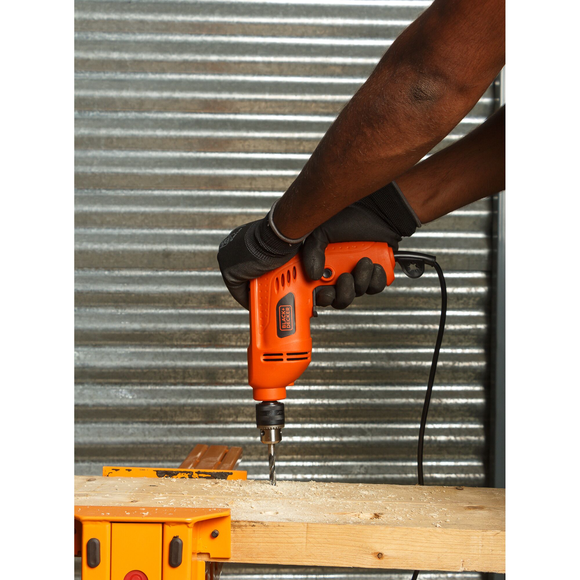 BLACKDECKER BD10RD orange electric drill used to drill into wood, shown in action shot.