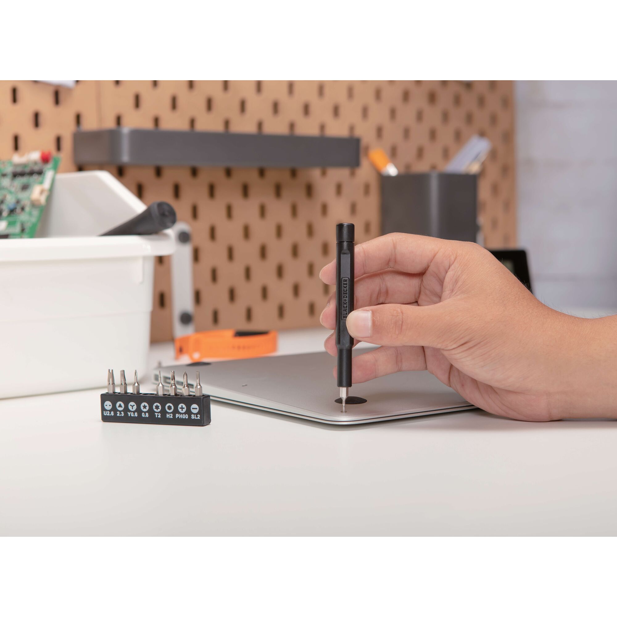 BLACKDECKER BD40K27 precision screwdriver set on desk with bits, hand using screwdriver on laptop.