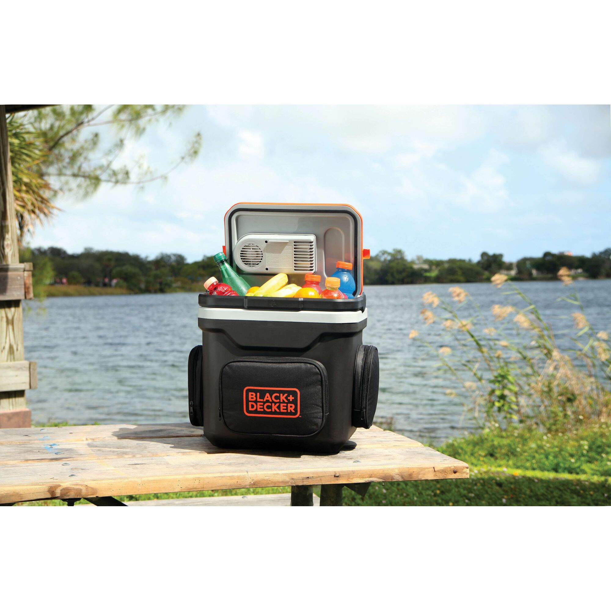 BLACK+DECKER BDC24L portable cooler filled with drinks and snacks shown outdoors by a lake.