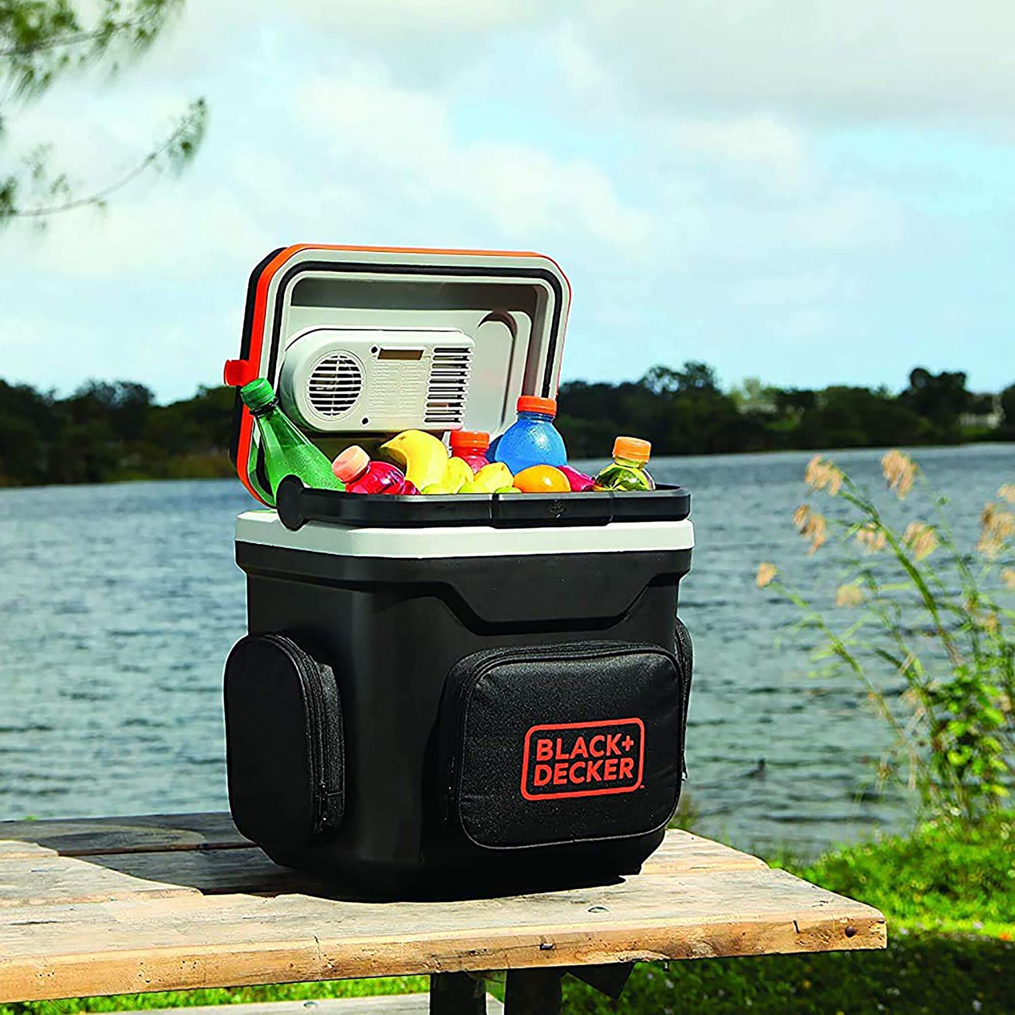 Photo of BLACKDECKER BDC24L portable cooler with drinks and fruit, open-lid, outdoors by a lake.
