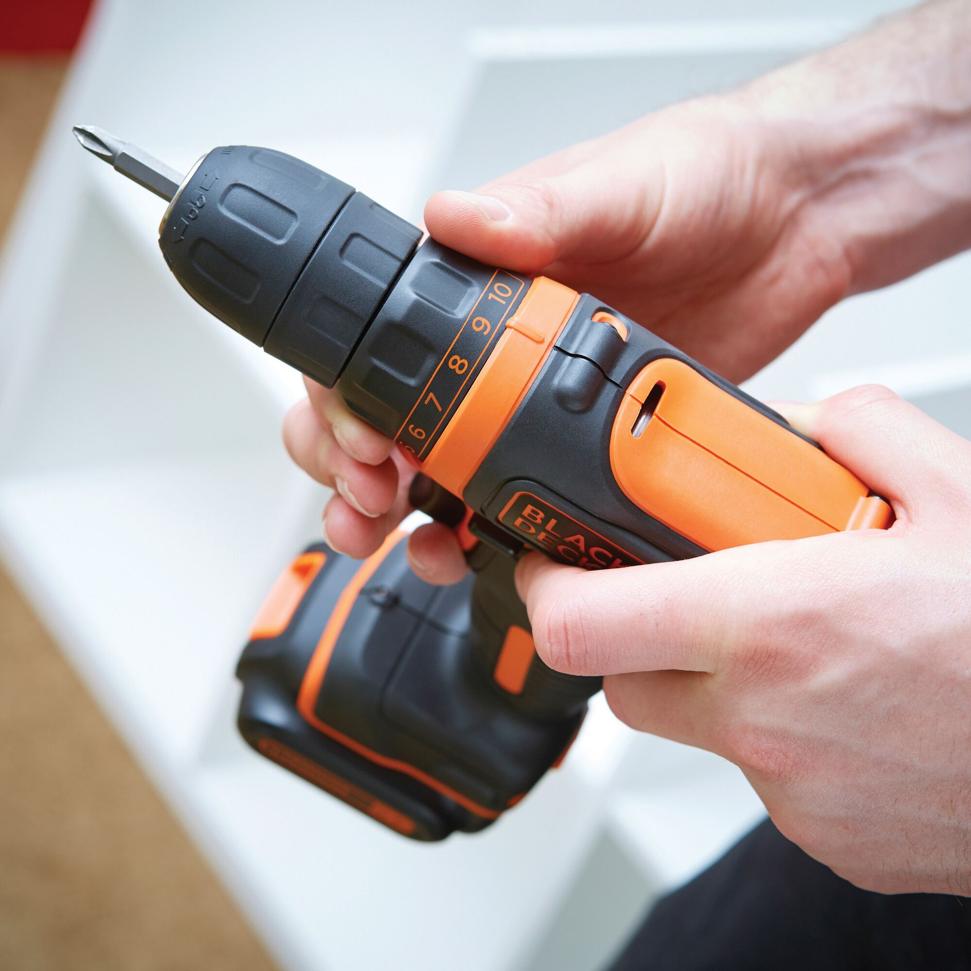 BLACKDECKER BDCDD12K cordless drill with orange and black design held in hand, side angle.