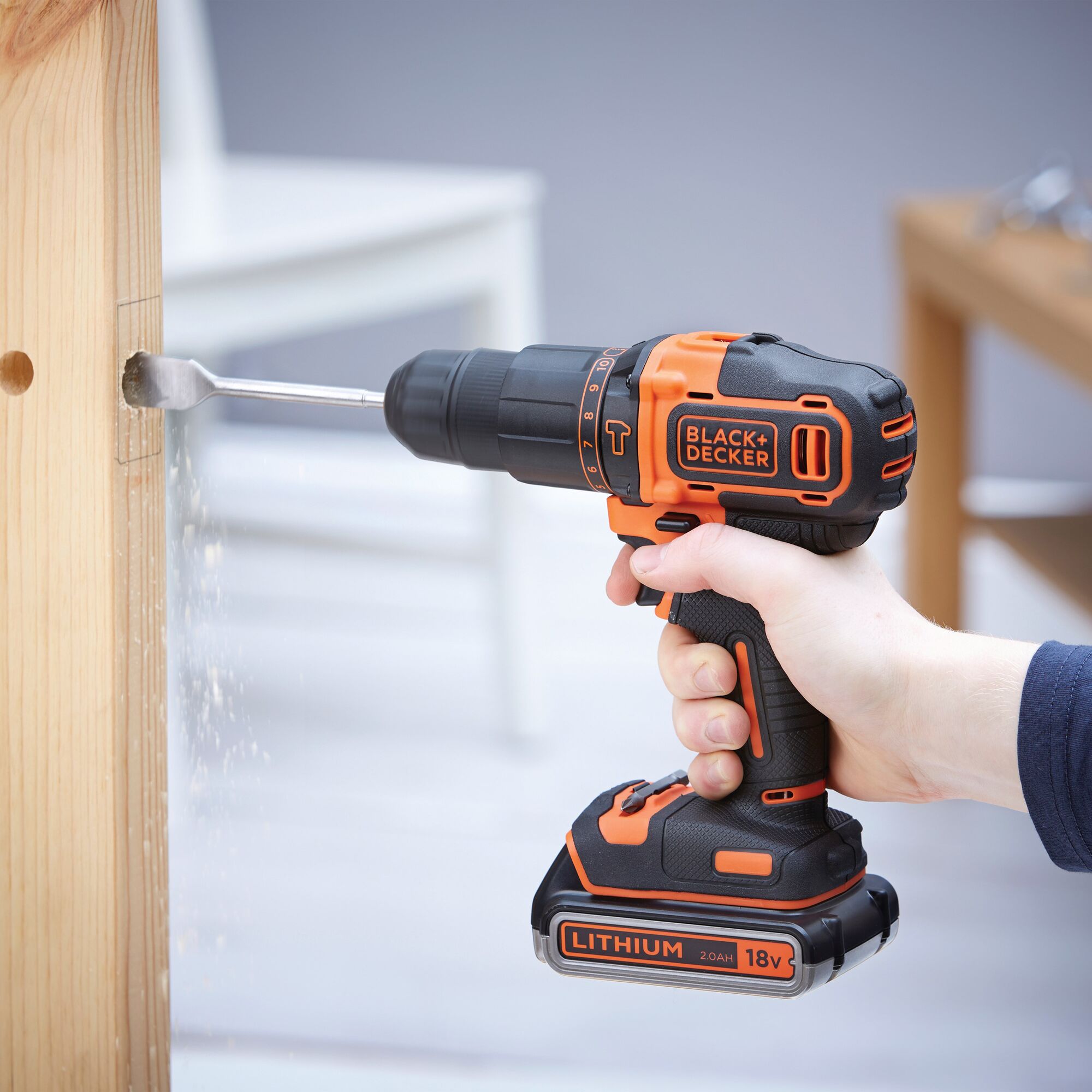 Photo of BLACKDECKER BDCHD18K1B cordless drill, black and orange, drilling into wood indoors.