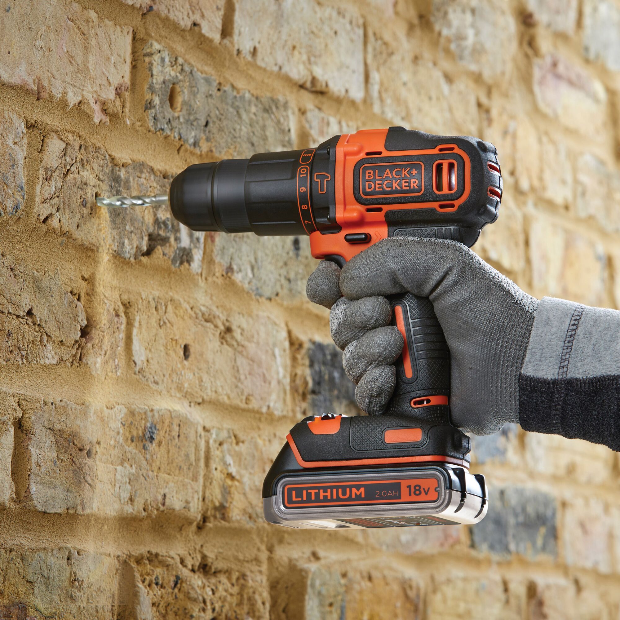 BLACKDECKER BDCHD18K1B cordless drill in use on a brick wall, 18V lithium battery, close-up side angle.