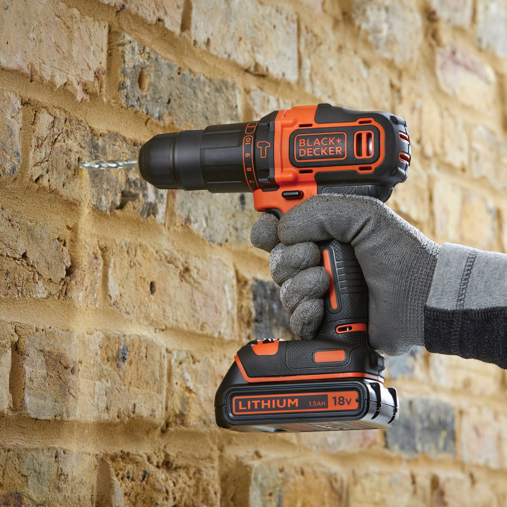 BLACKDECKER cordless drill BDCHD18K drilling into brick wall, orange and black, lithium 18V battery.