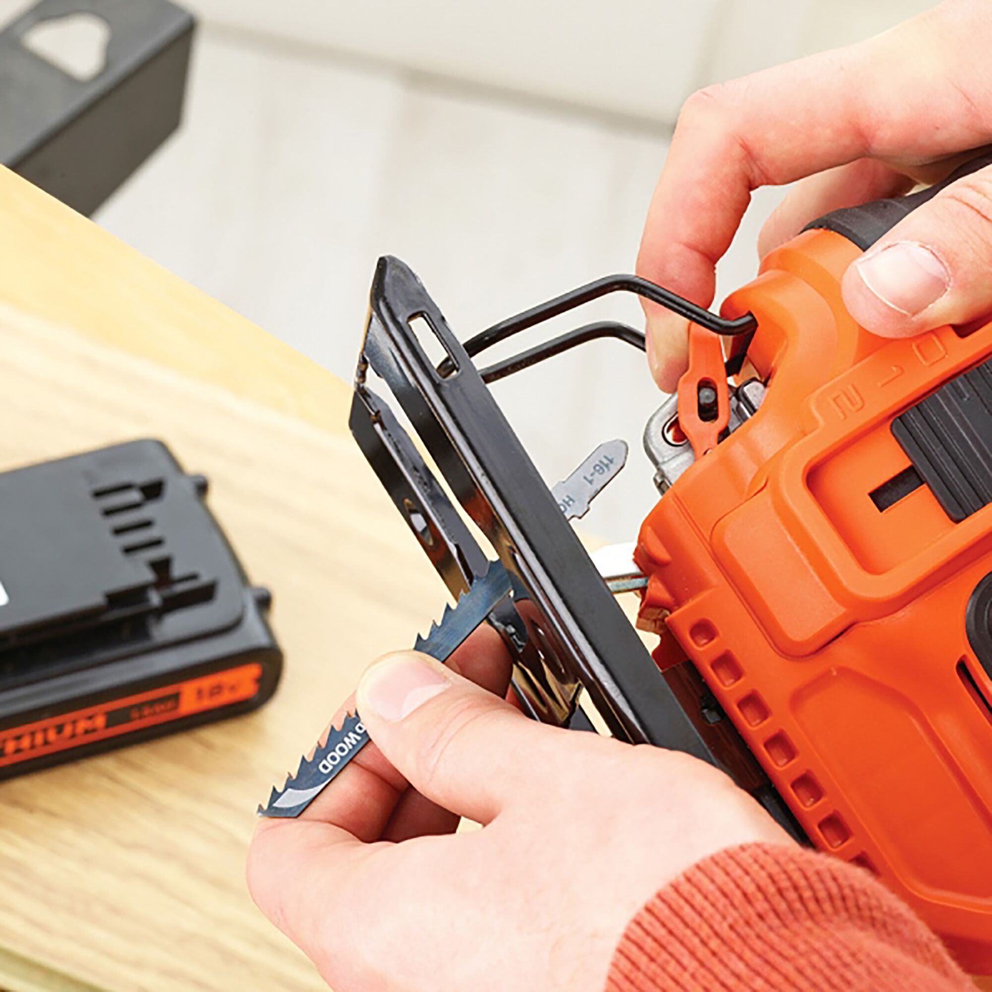 BLACKDECKER BDCJS18 jigsaw close-up with blade change, orange body and visible battery pack.
