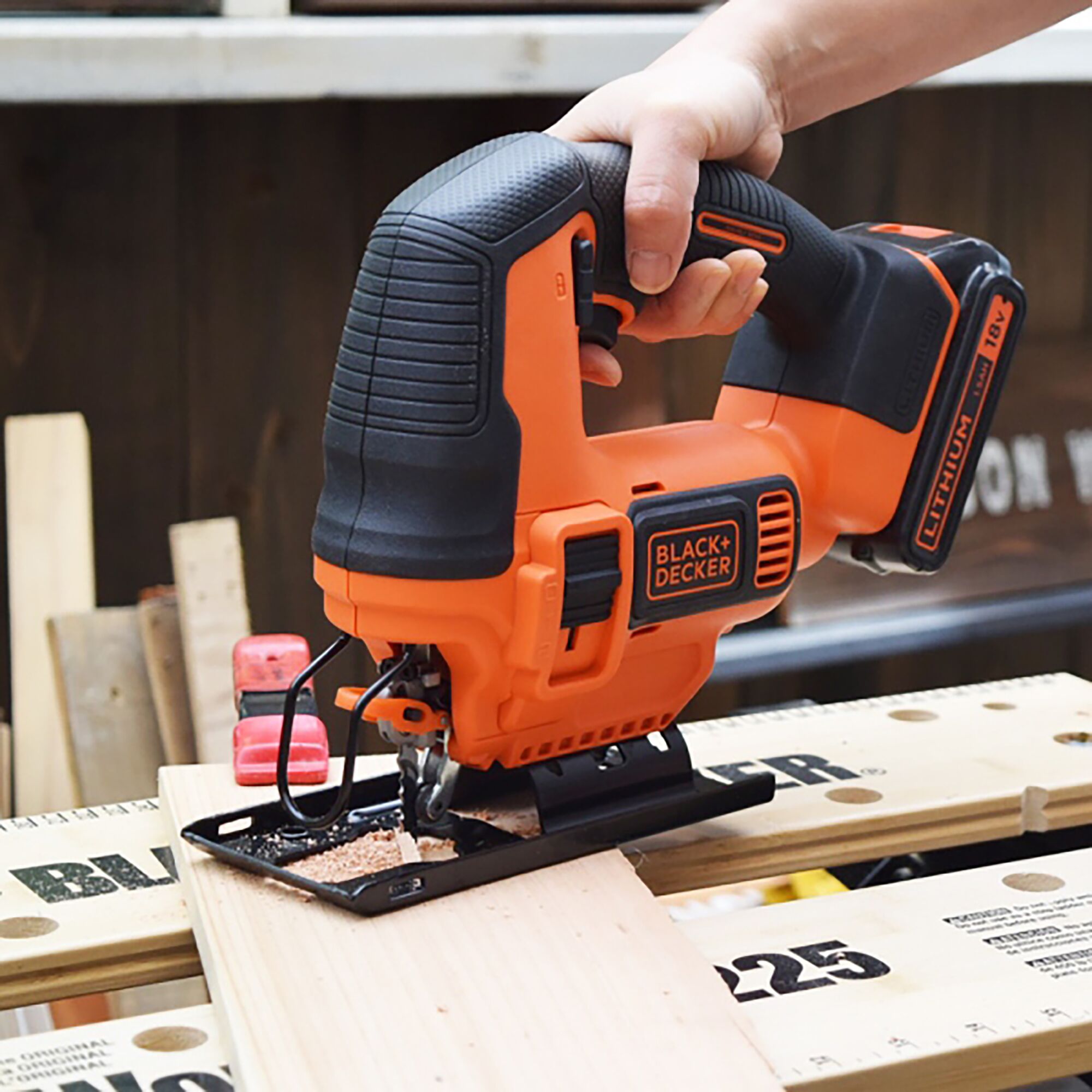 BLACKDECKER BDCJS18 cordless jigsaw cutting wood, orange and black design, handheld tool.