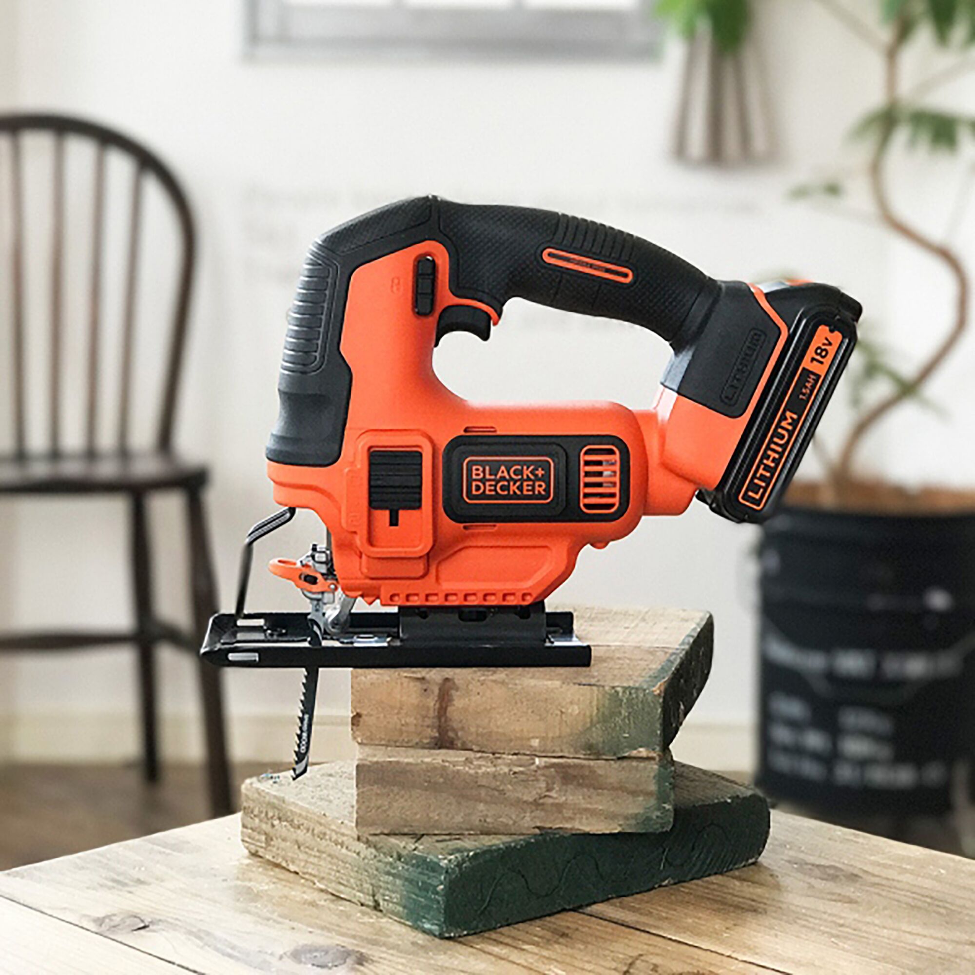 BLACK+DECKER BDCJS18 cordless jigsaw, orange and black, shown on wood blocks indoors.