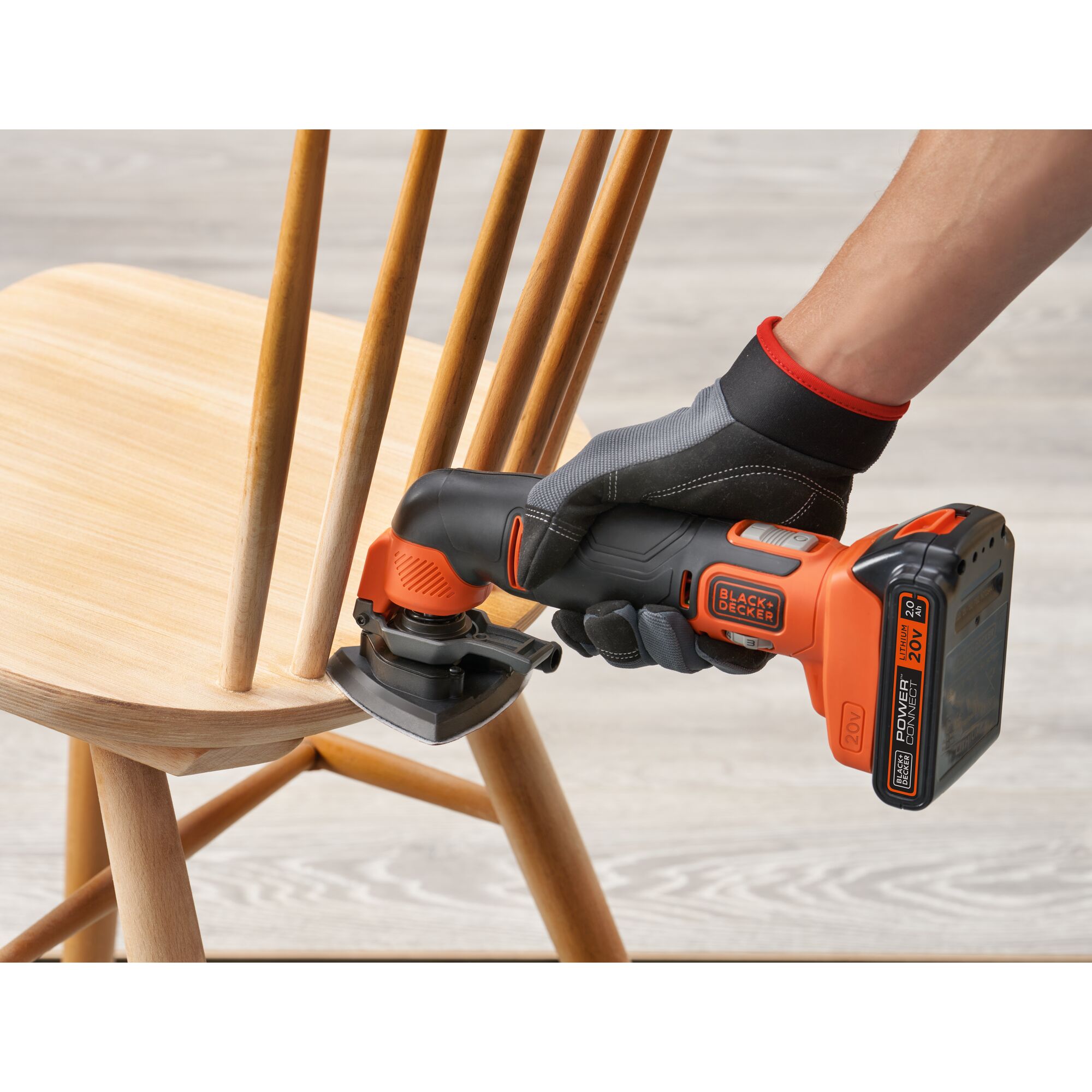 BLACKDECKER BDCOS18D1K cordless detail sander in use sanding wooden chair spindle, close-up side view.