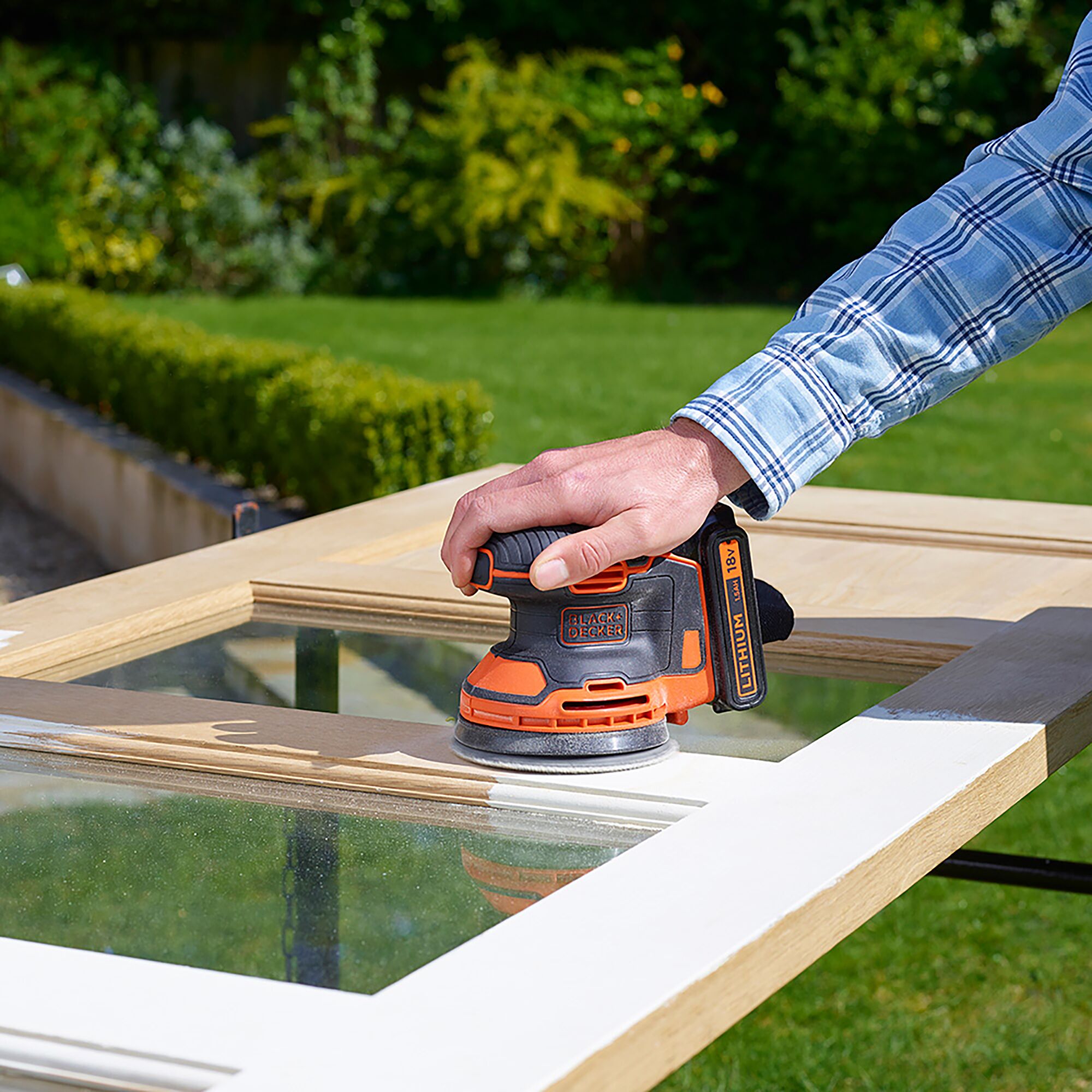 BLACKDECKER BDCROS18B cordless sander smoothing wood window frame outdoors.