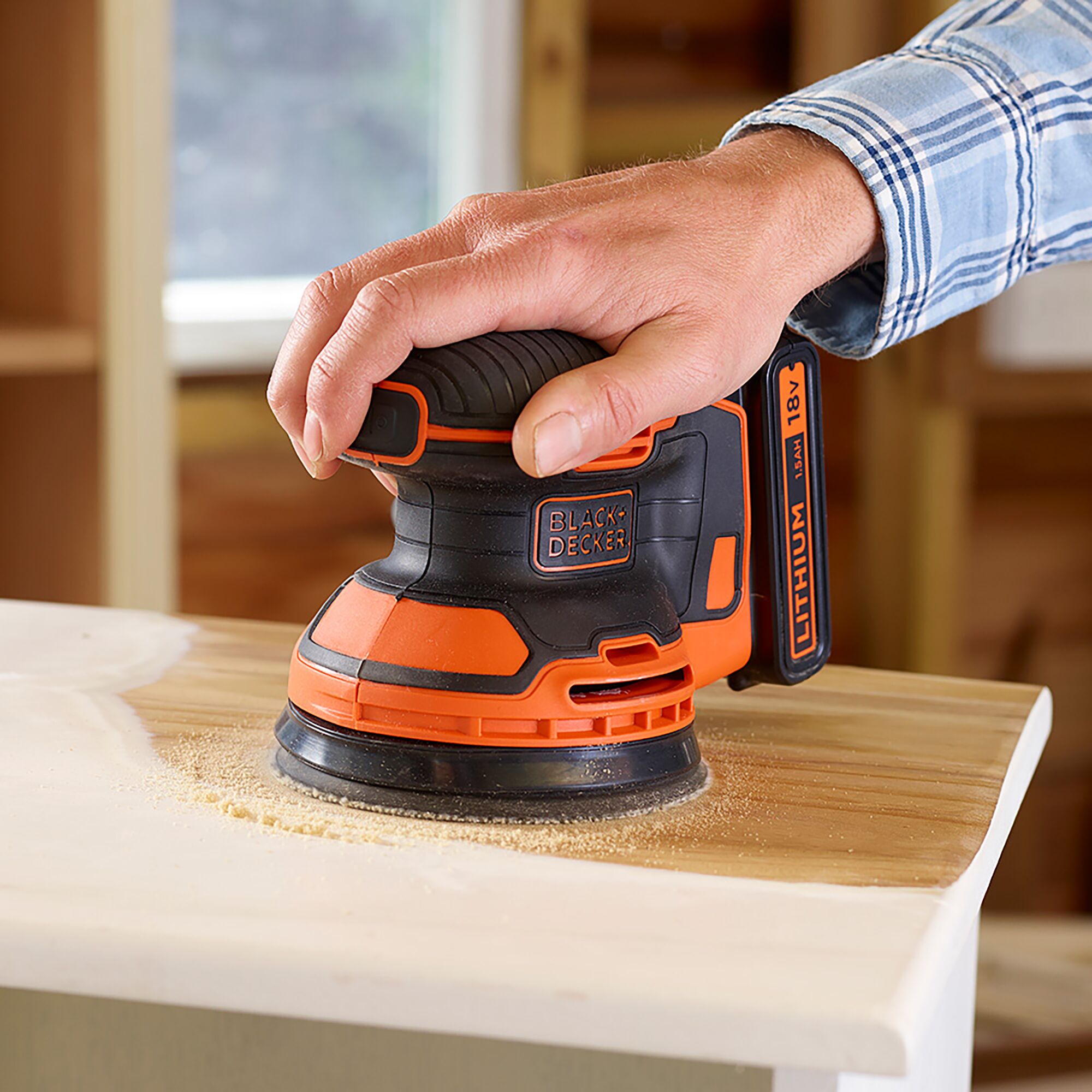 BLACKDECKER BDCROS18B cordless random orbital sander in use on wood surface, orange and black finish.