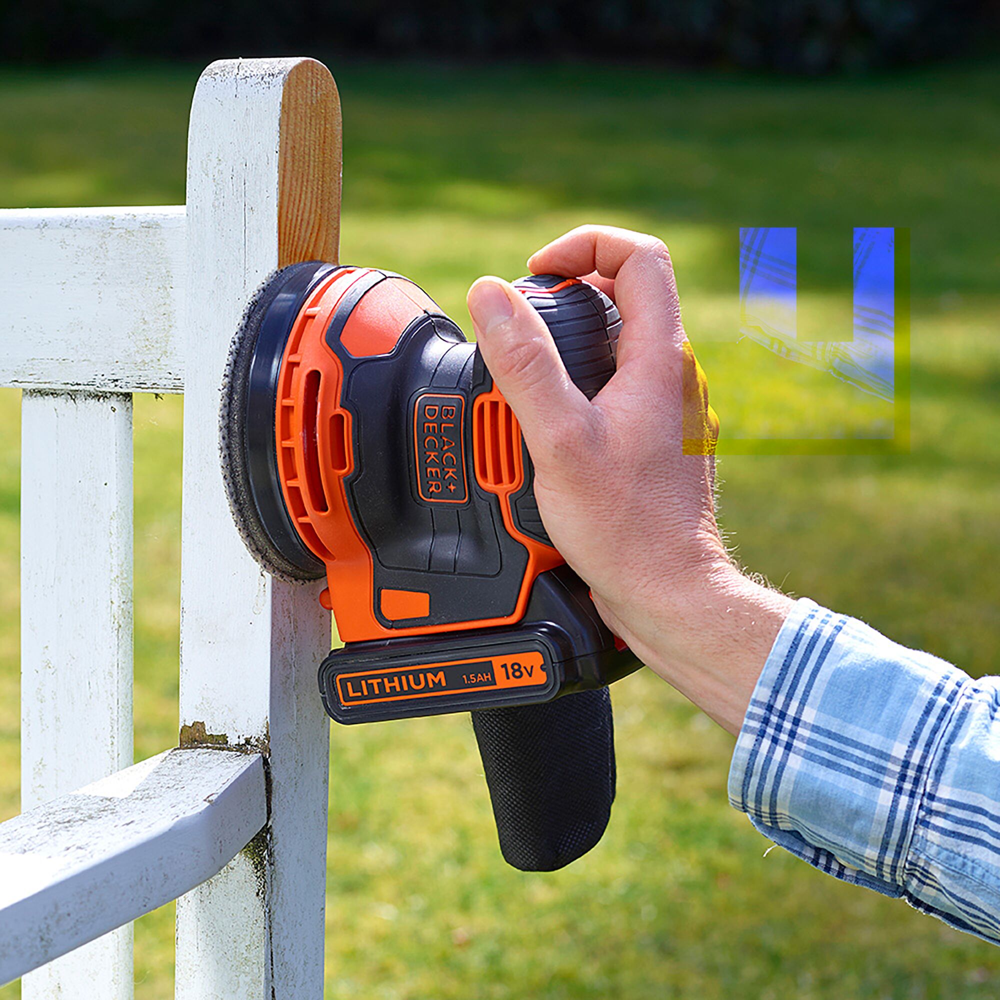 BLACKDECKER BDCROS18B 18V cordless random orbital sander sanding white wooden fence outdoors.