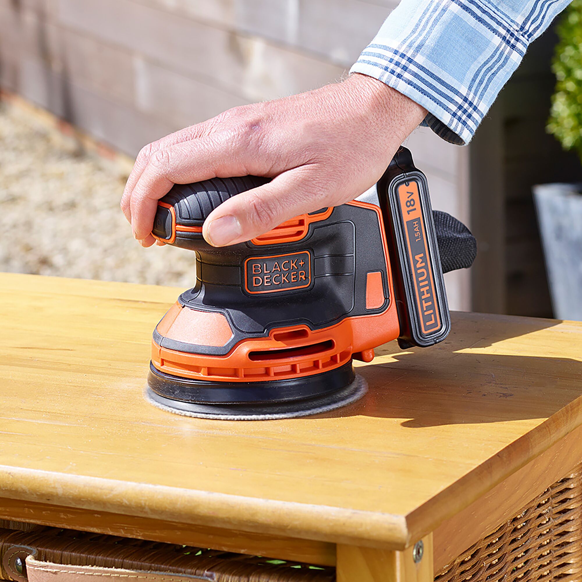 BLACKDECKER BDCROS18B cordless random orbital sander in use on wood surface, close-up angle.