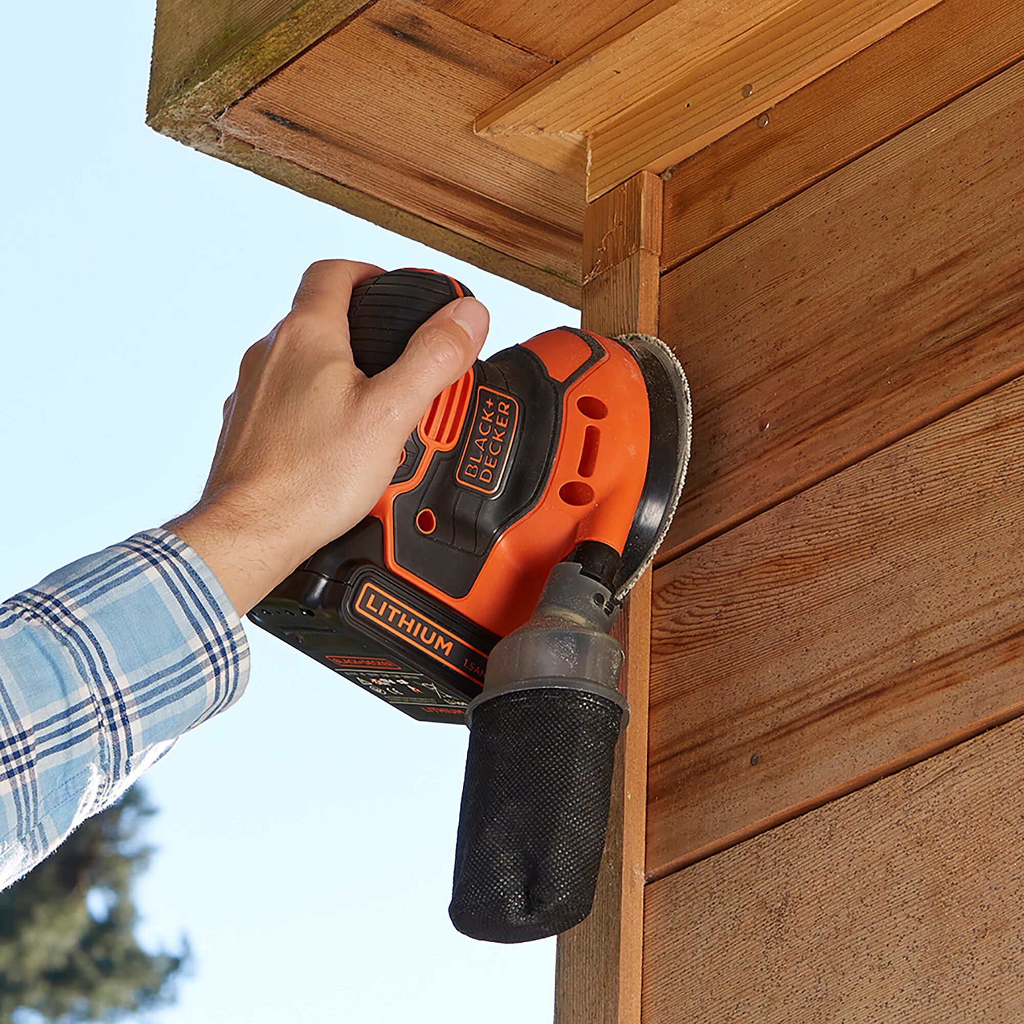 BLACKDECKER BDCROS18B cordless sander in use on wooden surface, close-up with visible dust bag.