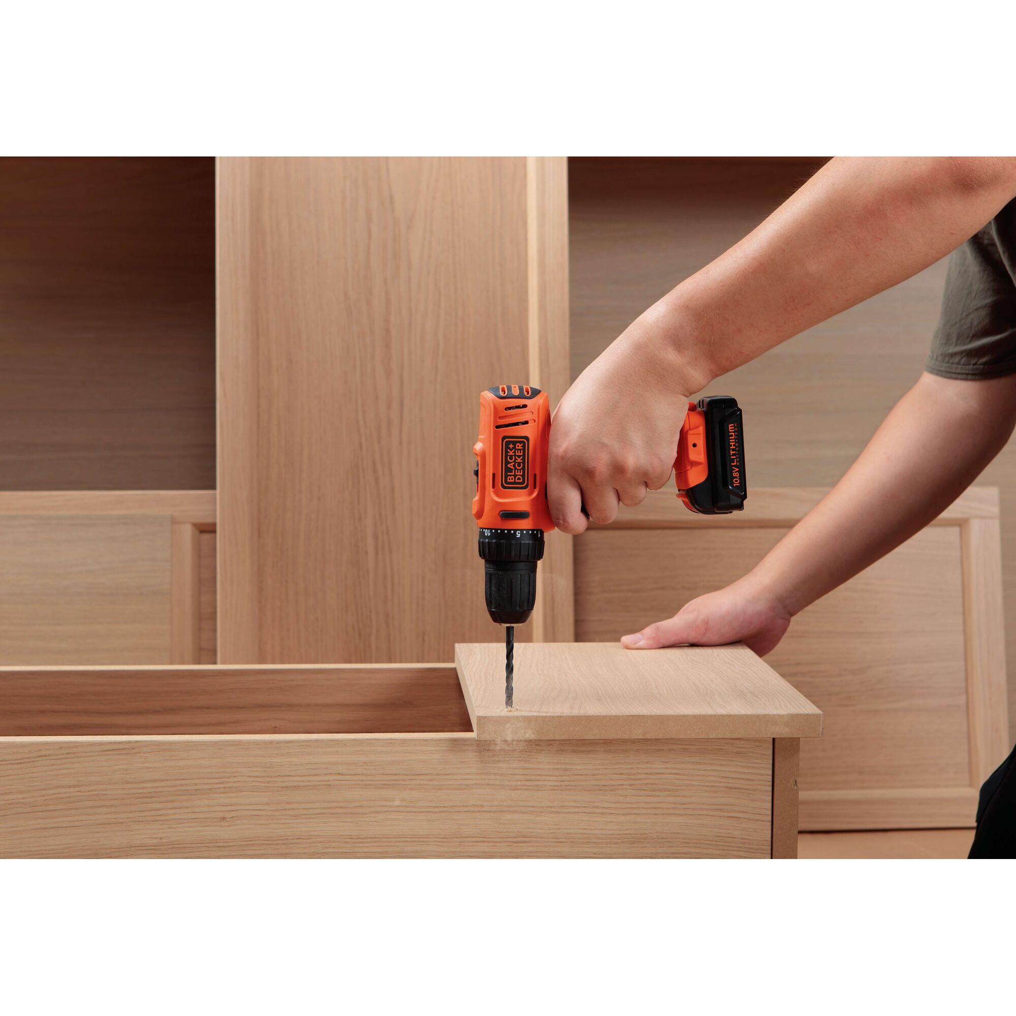 BLACKDECKER BDD12 cordless drill used on wooden furniture, close-up side angle.