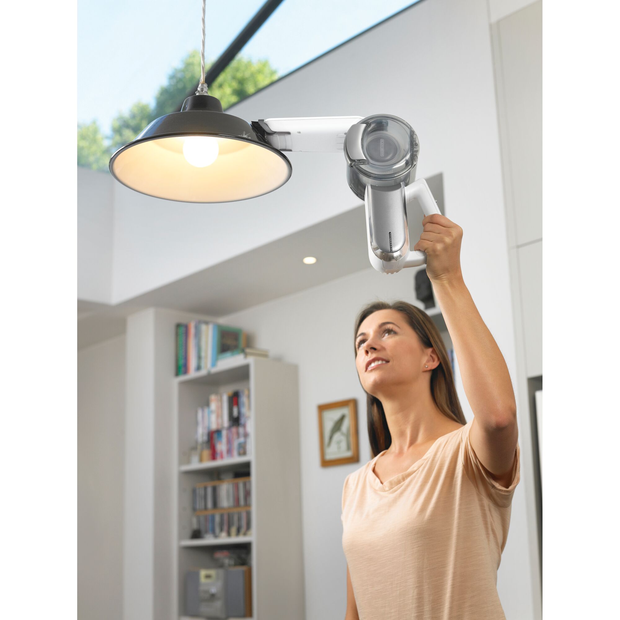 BLACKDECKER BDH1020CAC handheld vacuum cleaning a ceiling light in a modern home interior.