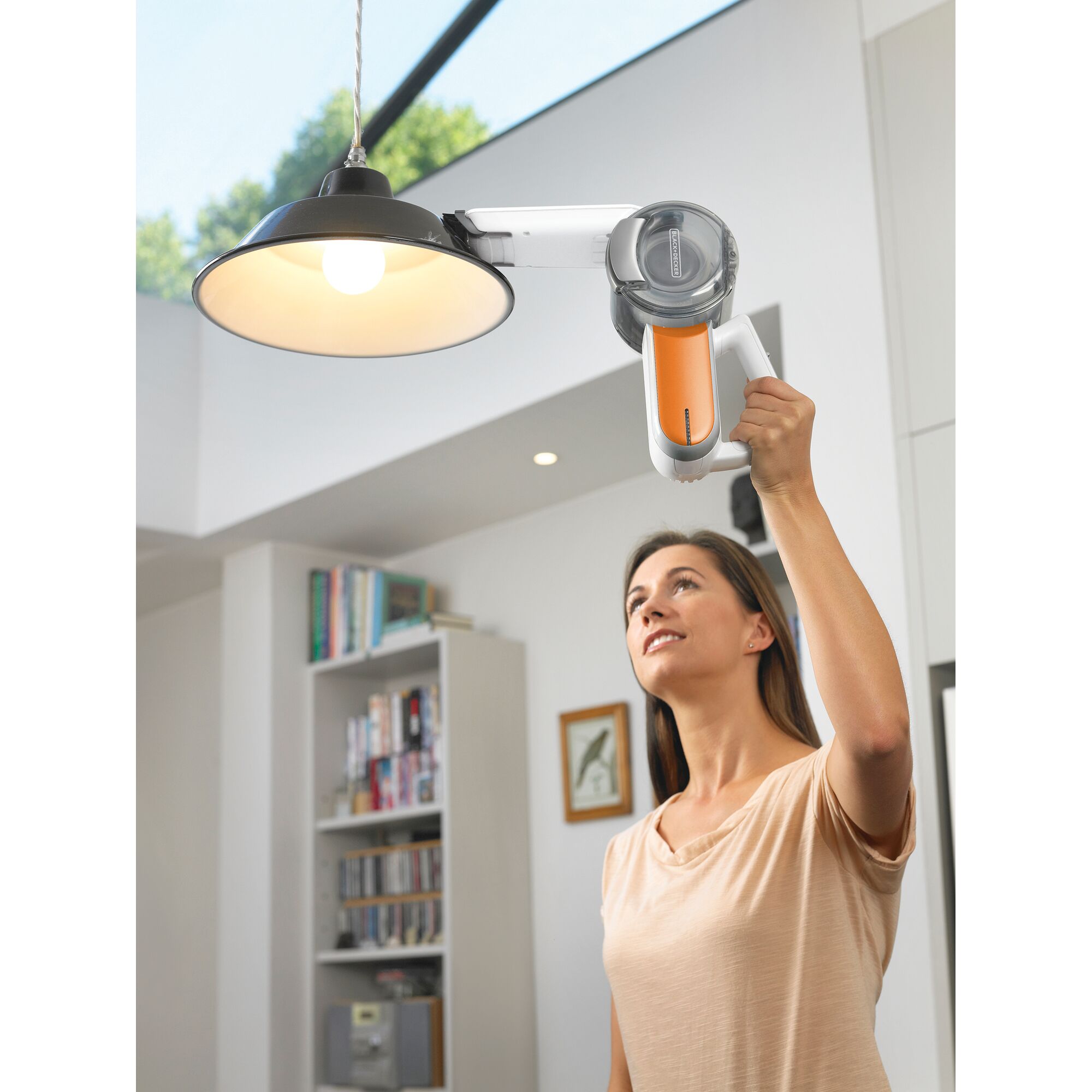 BLACK+DECKER BDH1020OAC handheld vacuum with orange filter used to clean a ceiling lamp indoors.
