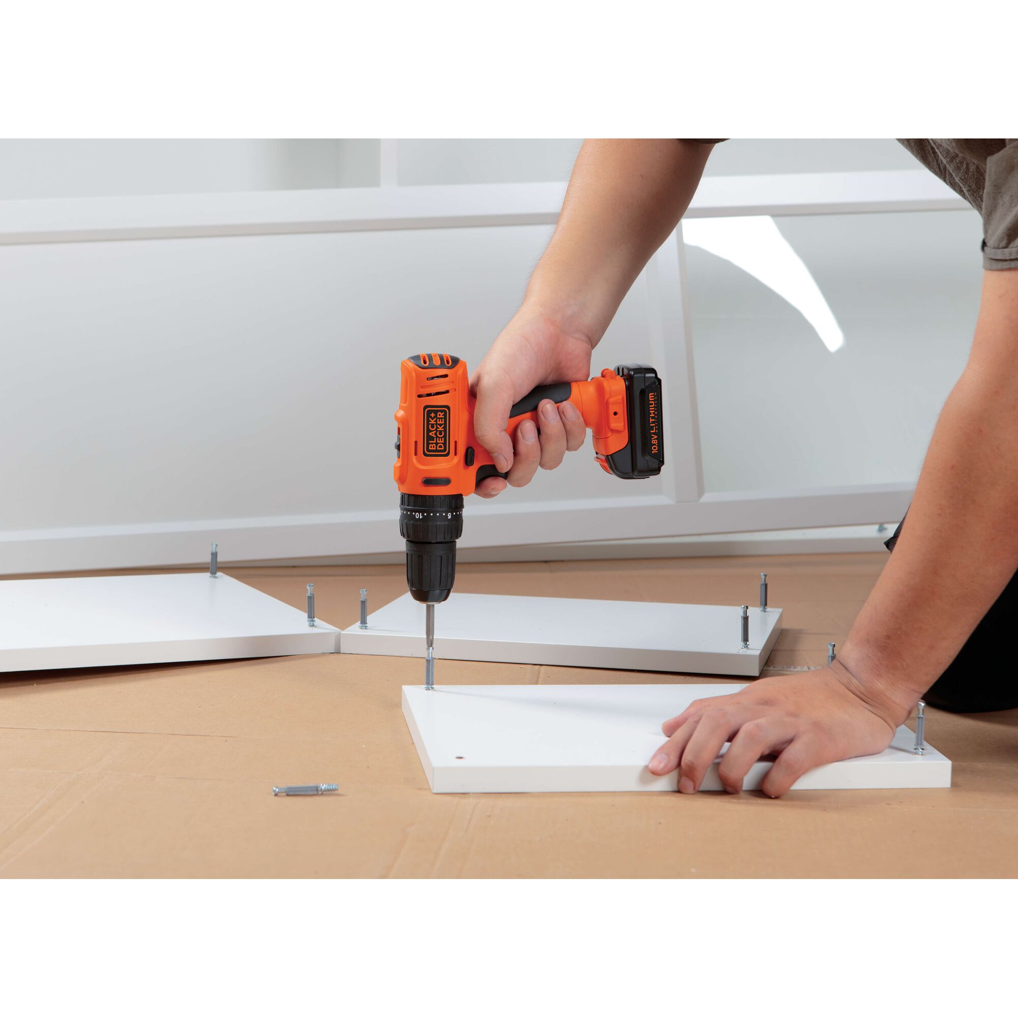 BLACKDECKER BDH12 cordless drill used to assemble white furniture panels, close-up view.