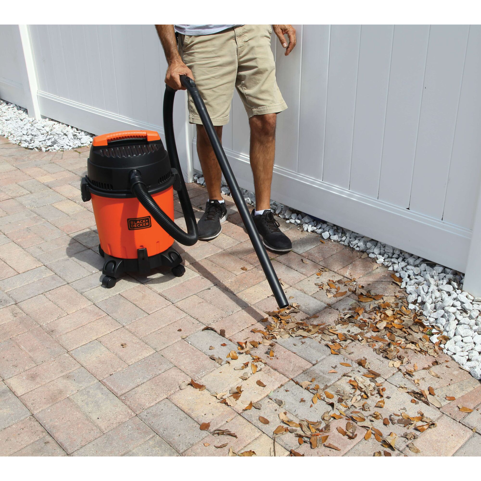 Photo of BLACKDECKER BDWD10 wet dry vacuum cleaning leaves on outdoor patio with person holding hose.