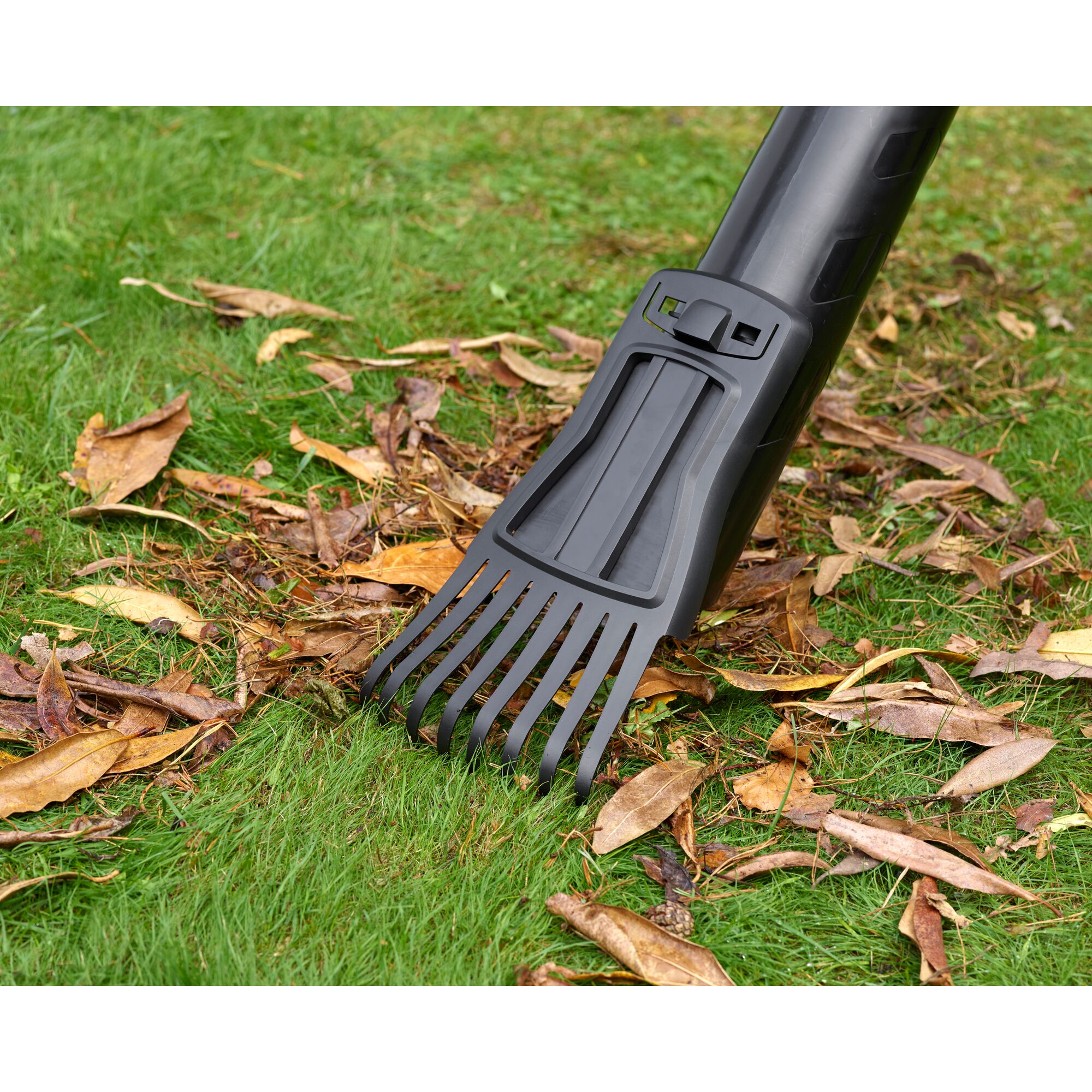 BLACKDECKER BEBLV301 leaf blower tube with rake attachment on grass with dry leaves, close-up angle.