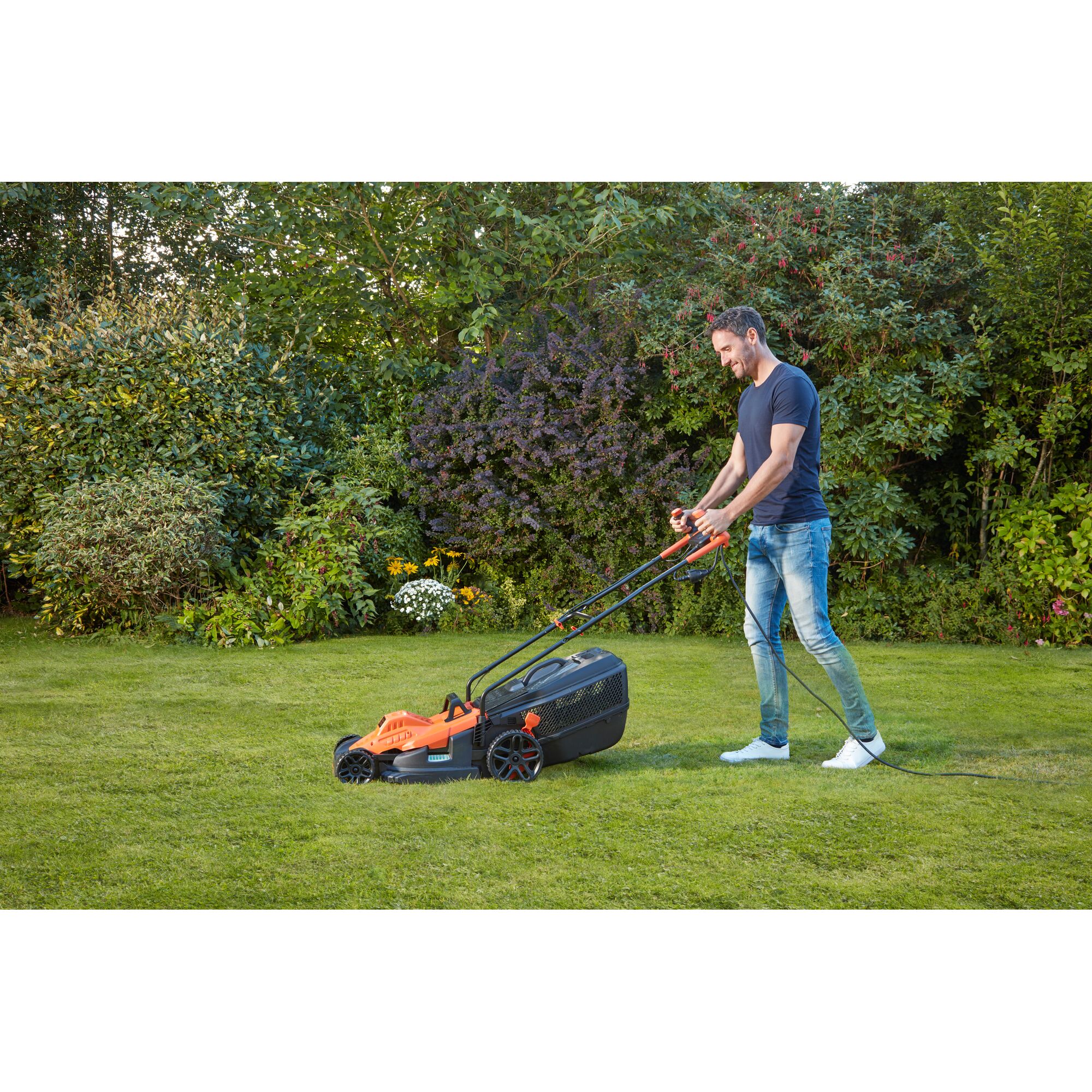 BLACKDECKER BEMW471BH lawn mower in use on grass, with person pushing, orange and black design.