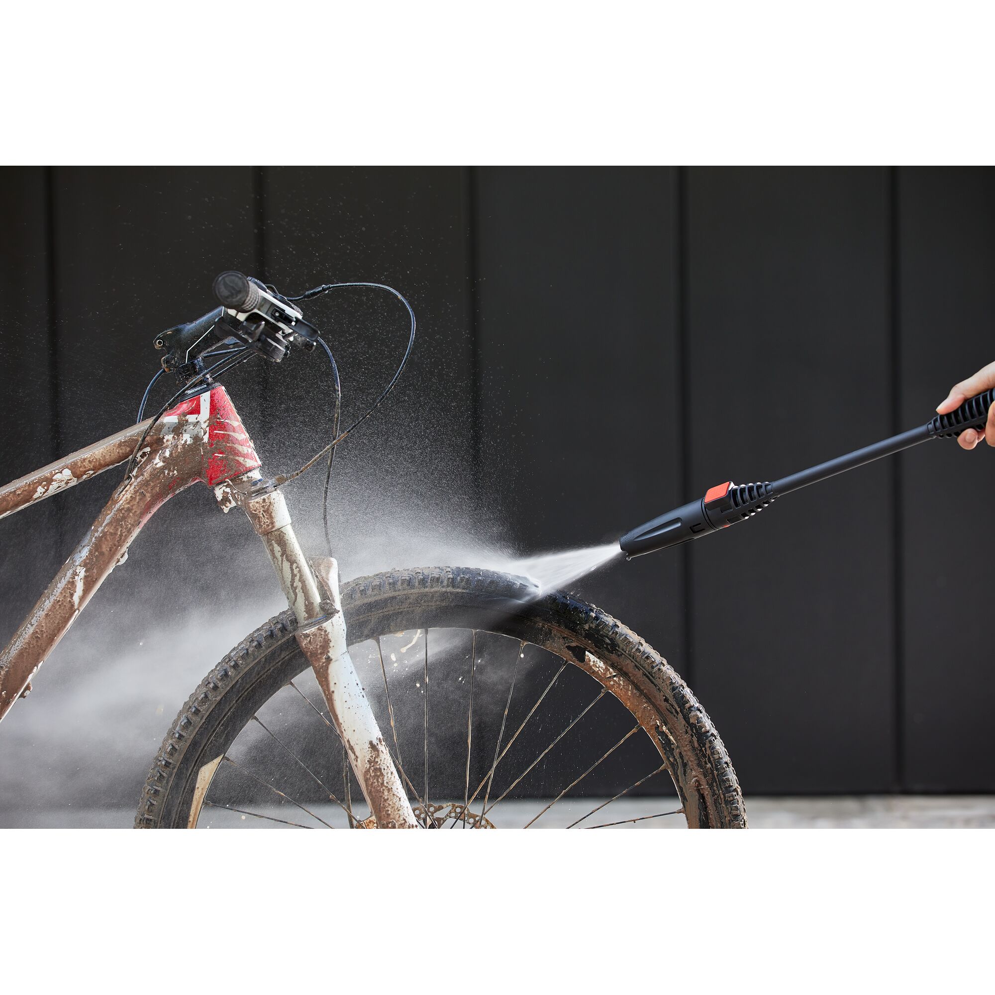 BLACKDECKER BEPW1600L pressure washer spraying water to clean muddy bicycle tire, front view.