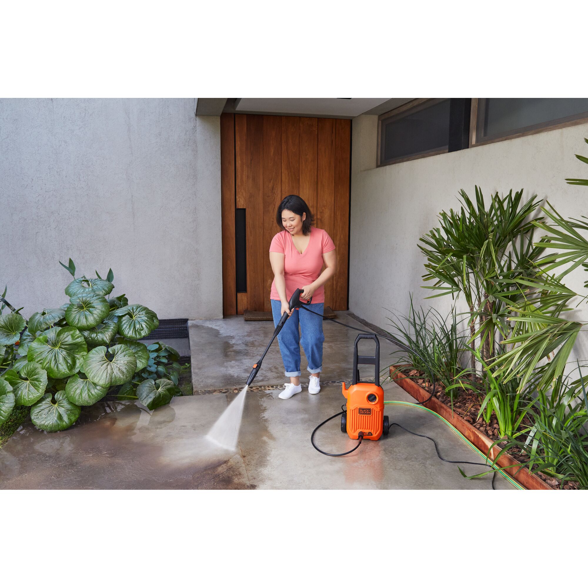 BLACKDECKER BEPW1600L pressure washer cleaning outdoor patio near plants.
