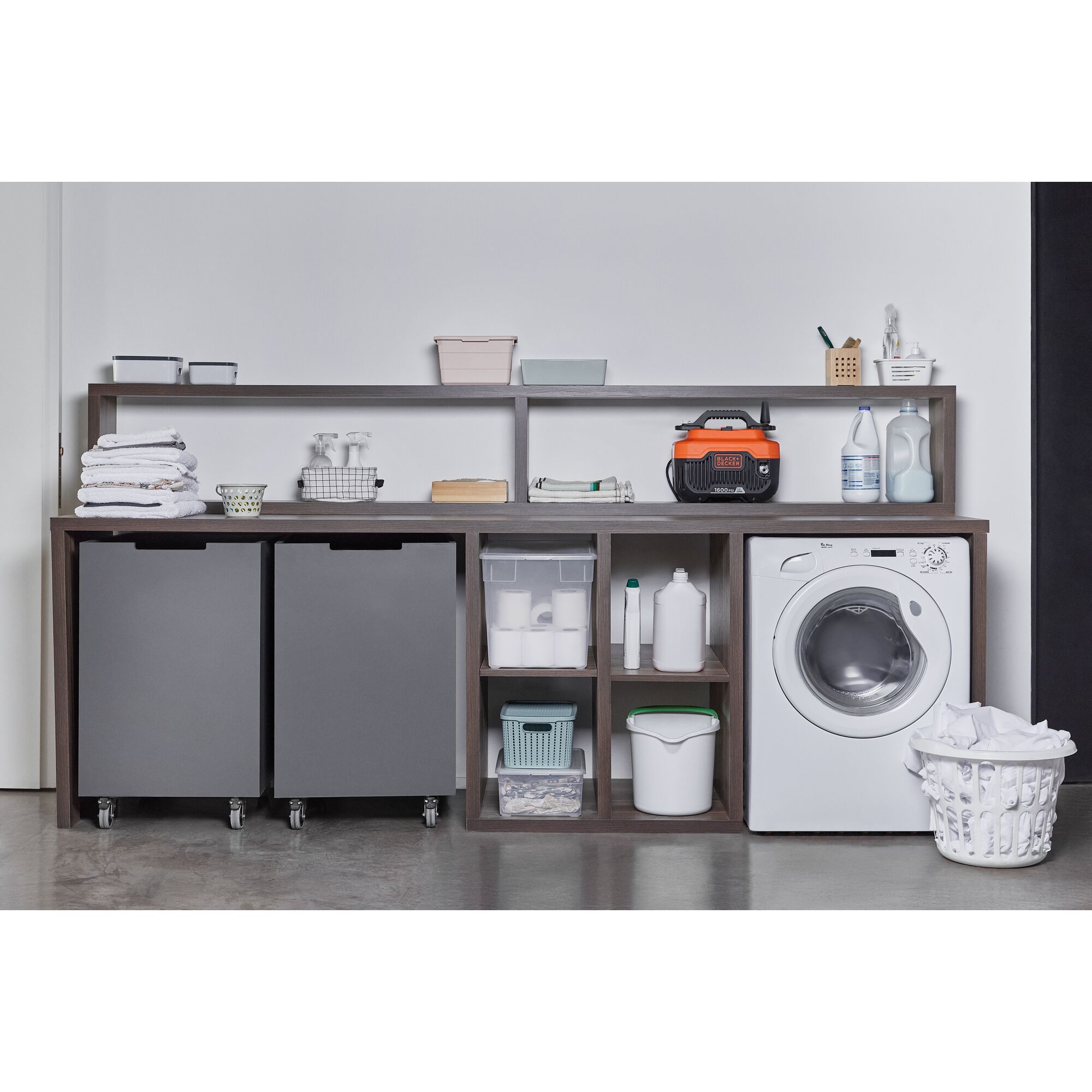 BLACKDECKER BEPW1600 pressure washer on laundry shelf with cleaning supplies, storage bins, and washing machine, straight angle.