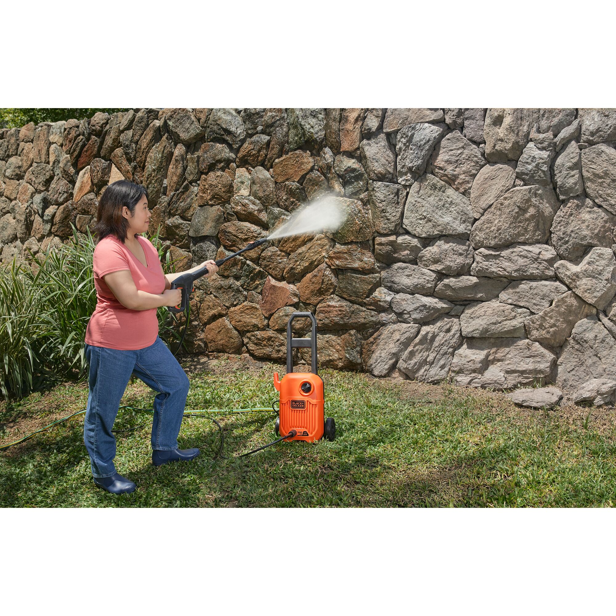 BLACKDECKER BEPW1750 pressure washer used to clean a stone wall outdoors.