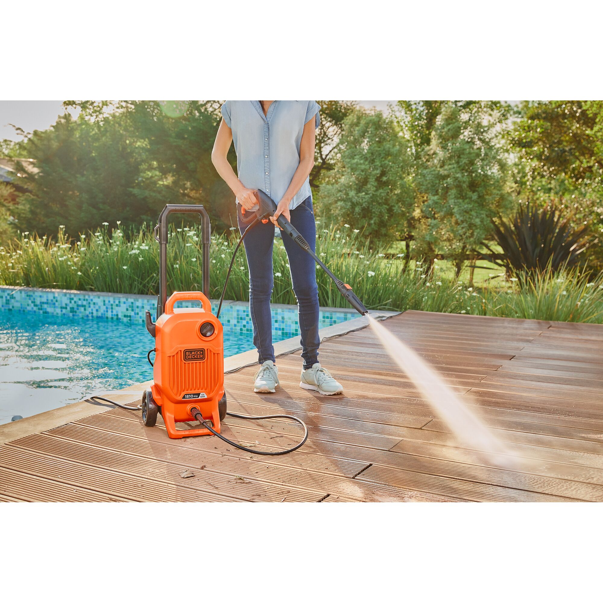 BLACKDECKER BEPW1800T pressure washer being used to clean a wooden deck near a pool.