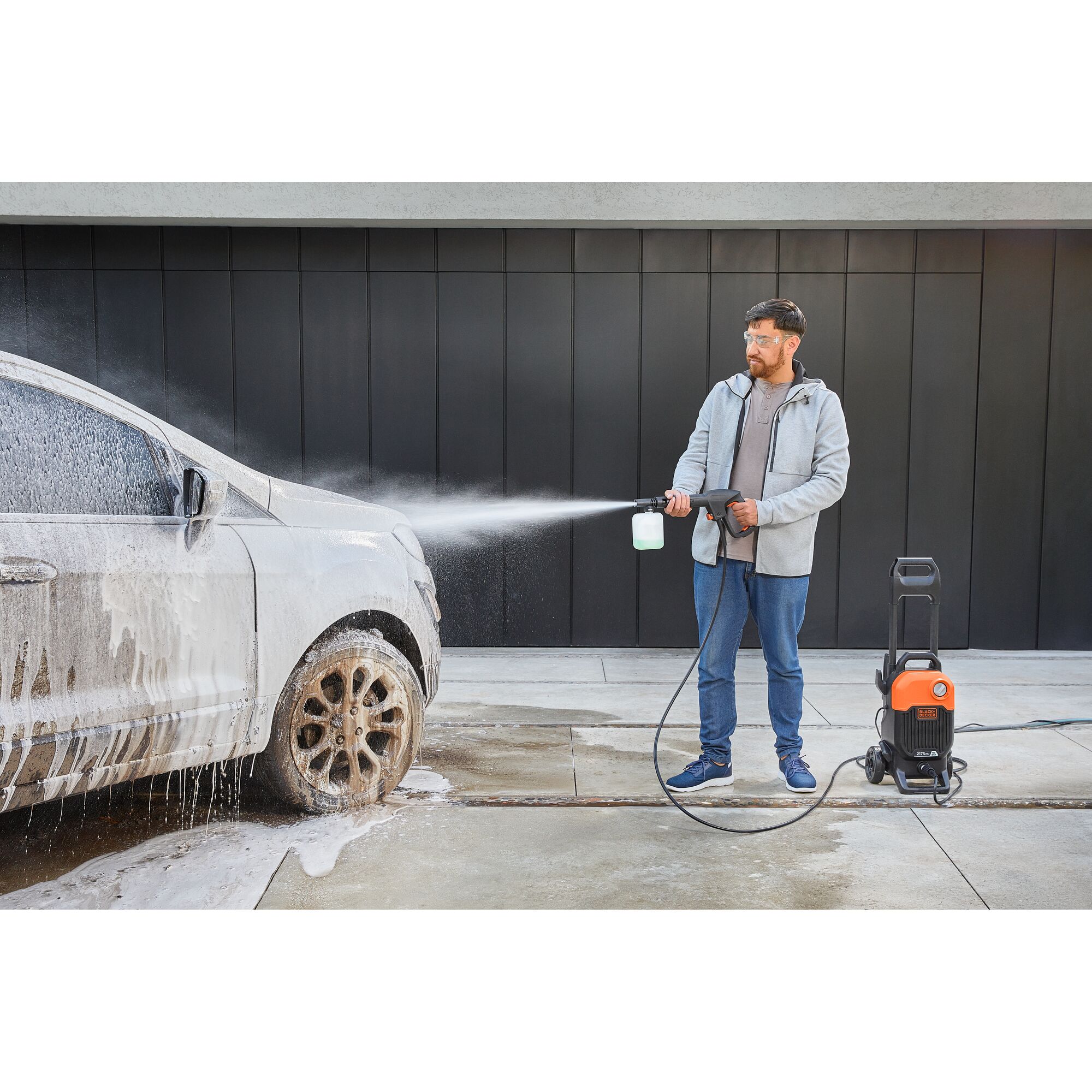 BLACKDECKER BEPW2200 pressure washer spraying foam on a car during cleaning, outdoor use.