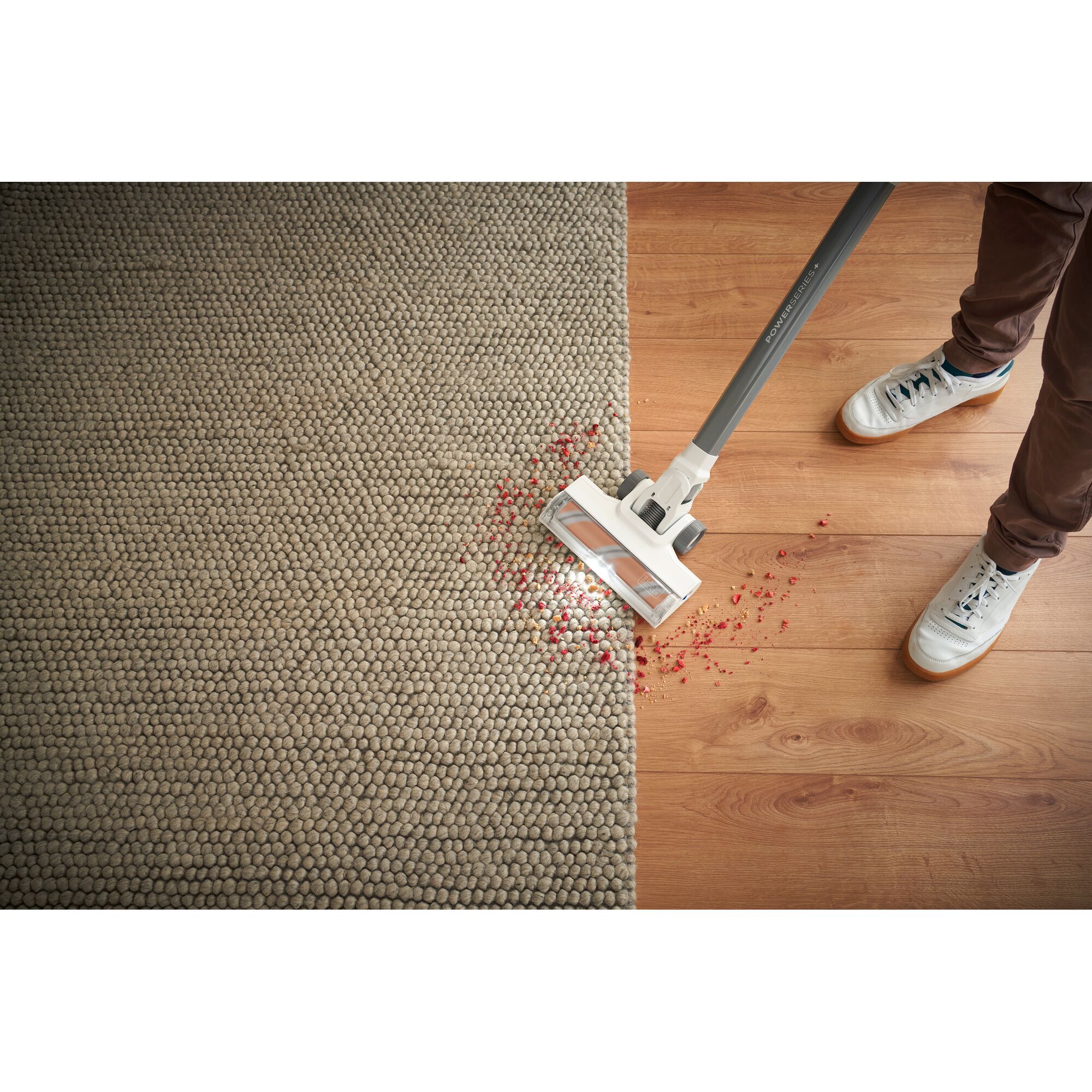 BLACKDECKER BHFEA18D2W stick vacuum cleaning red debris on carpet and wood floor, top view.