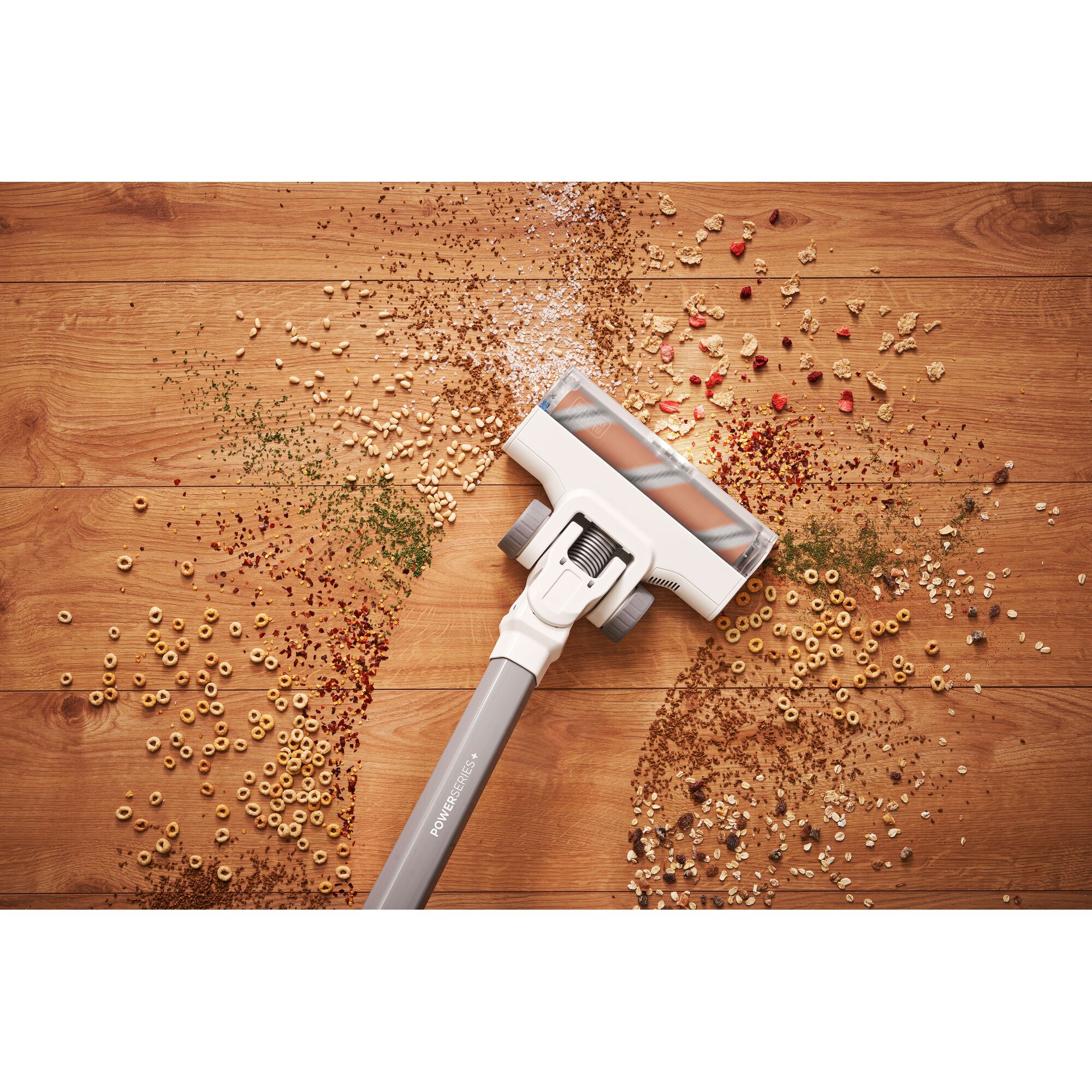BLACK+DECKER BHFEA18D2W cordless vacuum cleaner head cleaning various dry debris from wooden floor, top view.