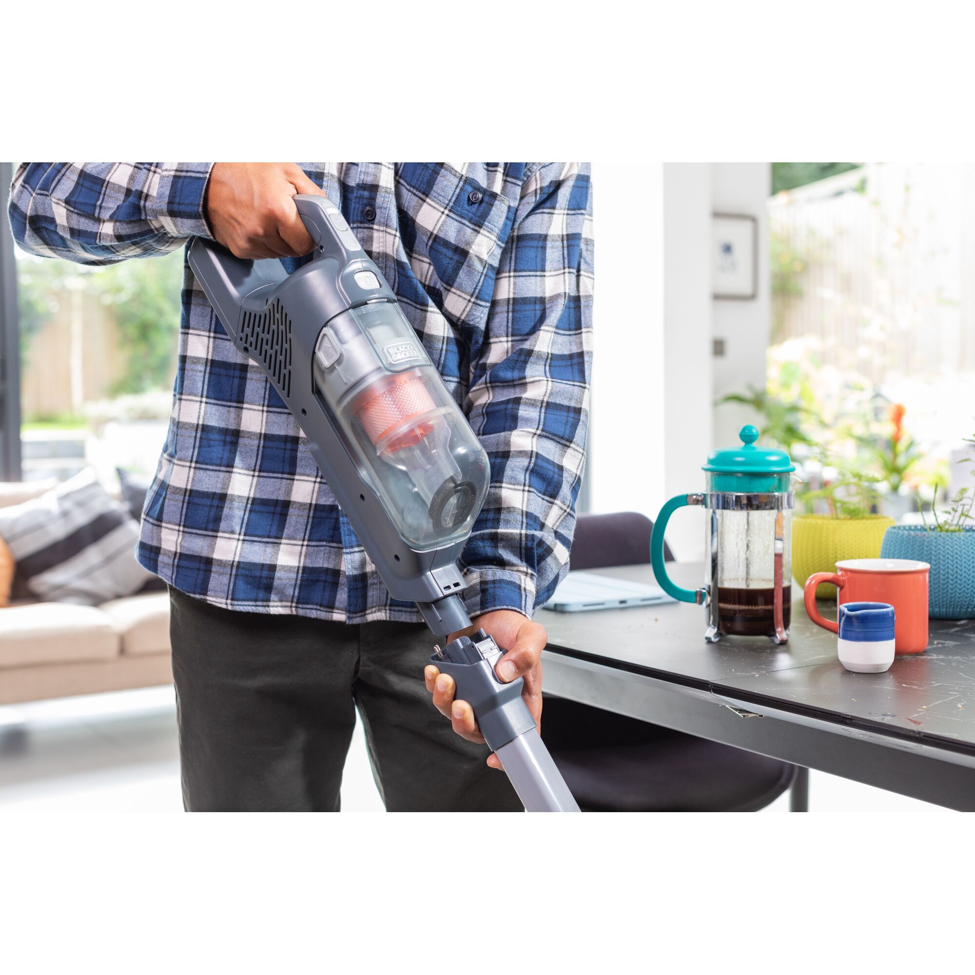 BLACKDECKER BHFEA520J cordless vacuum in use next to coffee cups and French press on tabletop.
