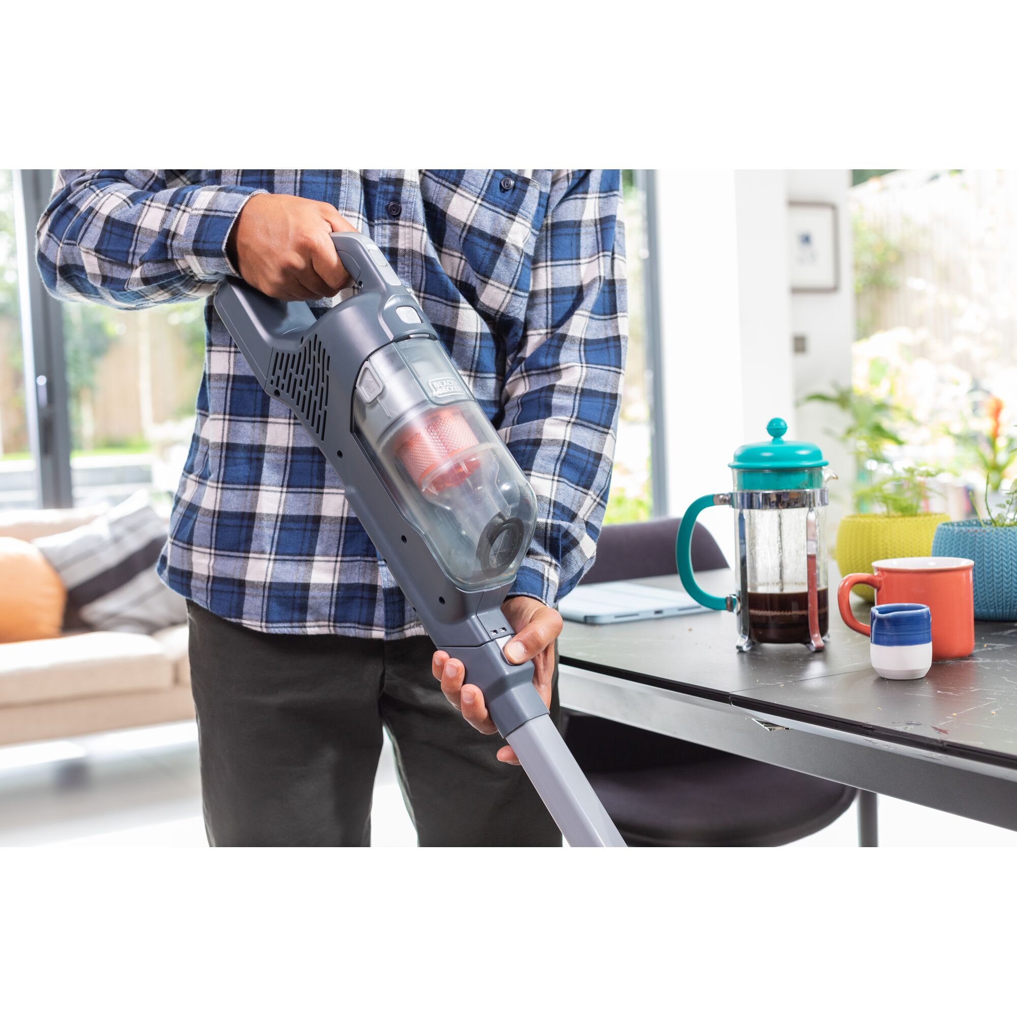 BLACKDECKER BHFEA520J cordless vacuum cleaner held in hand near table with coffee cups.