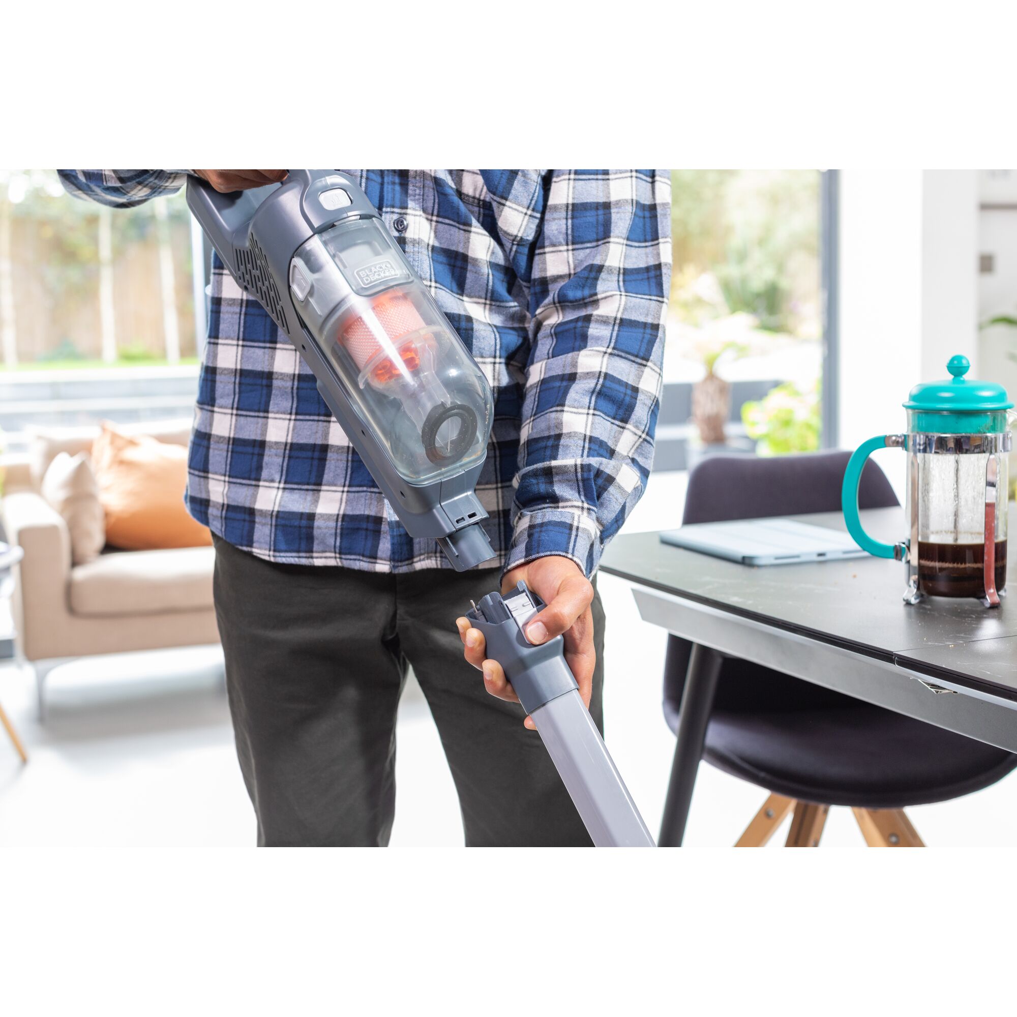 BLACKDECKER BHFEA520J cordless vacuum cleaner held by person indoors near table with coffee press.
