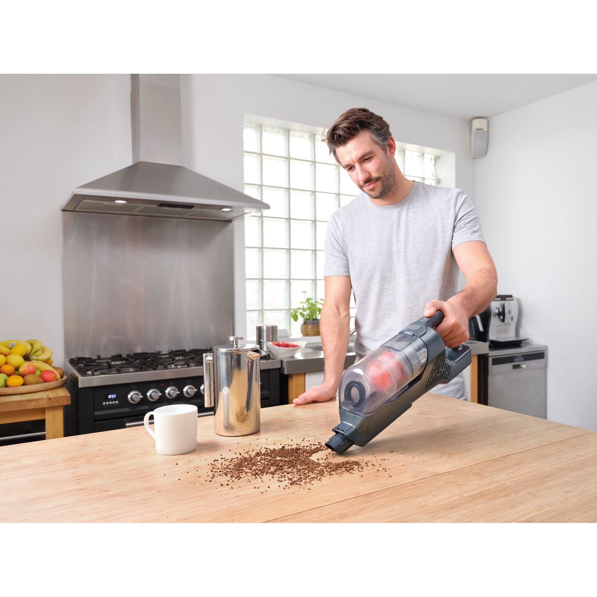 BLACKDECKER BHFEA520J handheld vacuum being used to clean coffee grounds on wooden kitchen table.