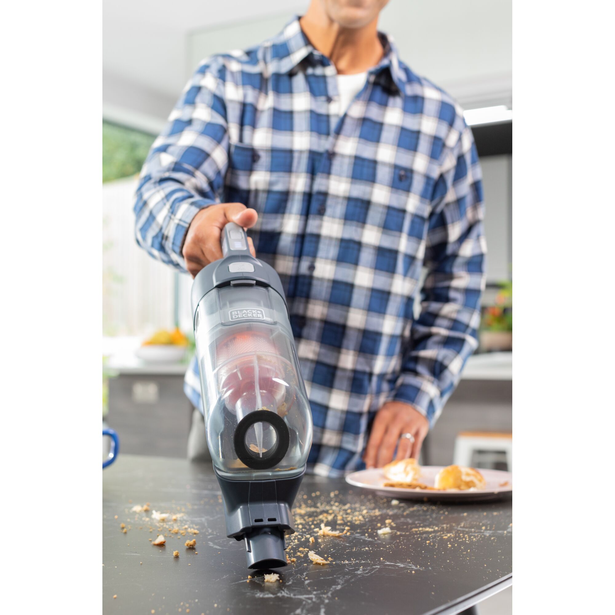 BLACK+DECKER BHFEA520J hand vacuum cleaning crumbs from kitchen table, close-up angle.